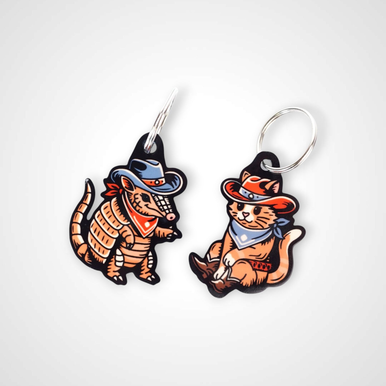 Cowboy armadillo cast acrylic keychain with double coil keyring. Shown on white background next to cowboy cat keychain.