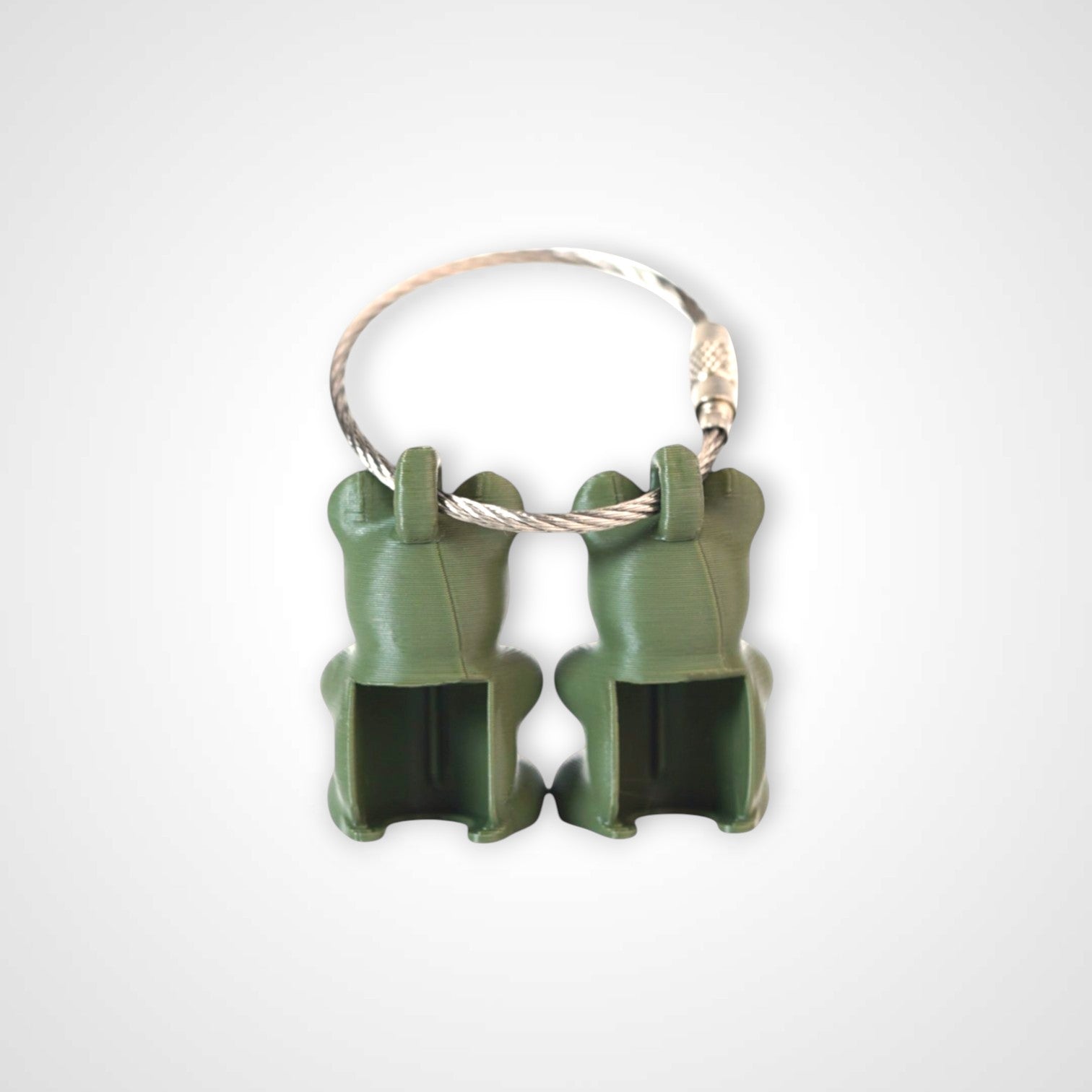 Two army green polylactic acid created using additive manufacturing gummy bear clips on steel cable keyring. Shown on a white background.