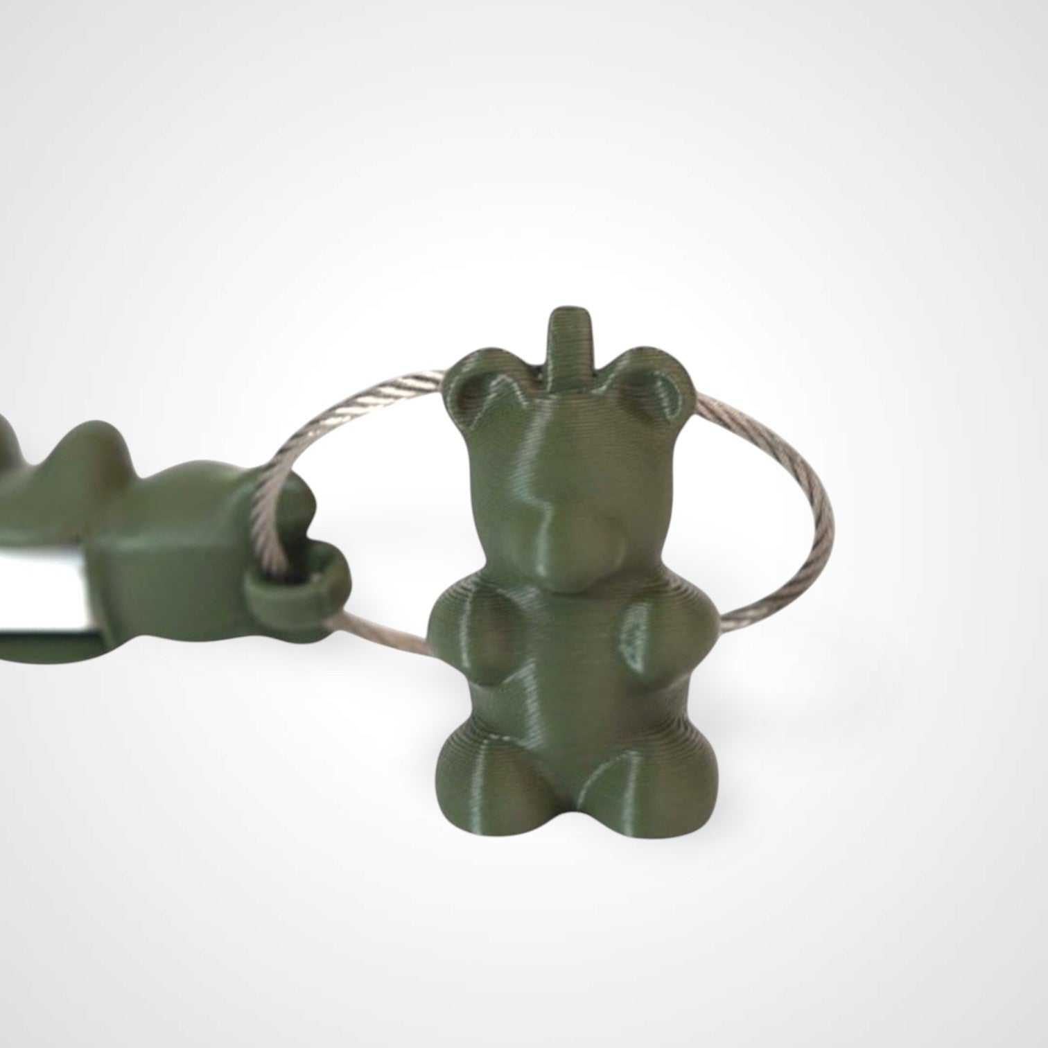 Two army green polylactic acid created using additive manufacturing gummy bear clips on steel cable keyring. Featured attached to a syringe. Shown on a white background.