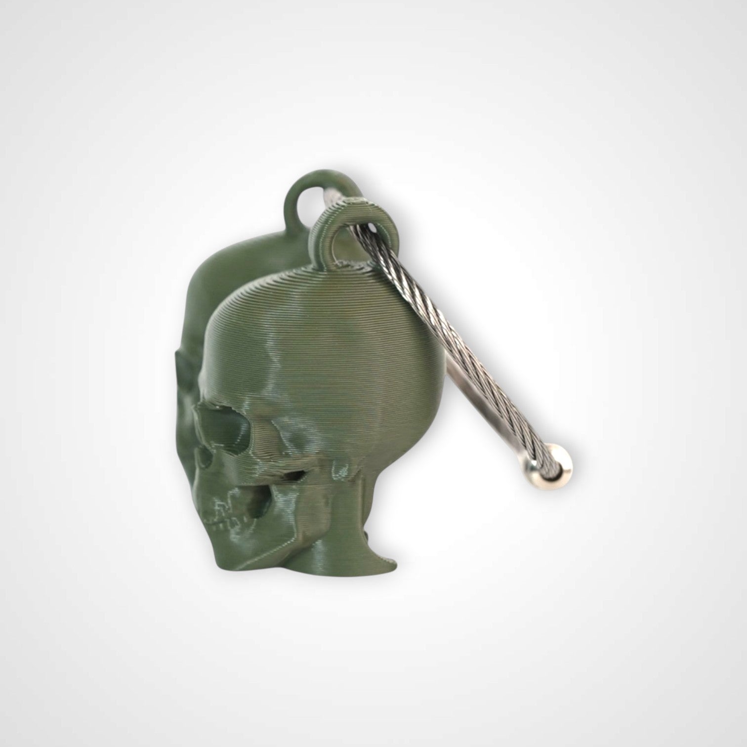 Two army green polylactic acid created using additive manufacturing skull cap clips on steel cable keyring. Shown on a white background.