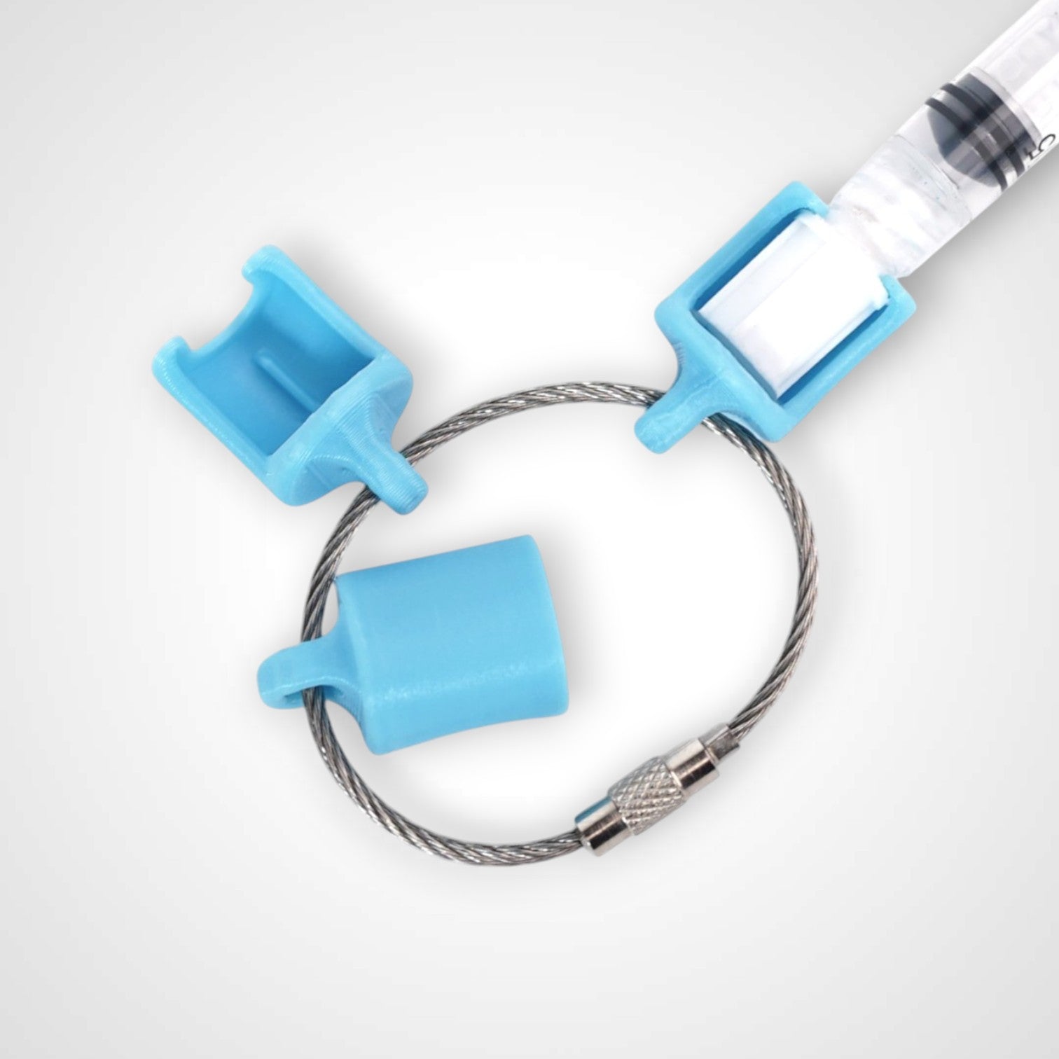 Three blue polylactic acid created using additive manufacturing classic cap clips on steel cable keyring. Featured attached to a syringe. Shown on a white background.