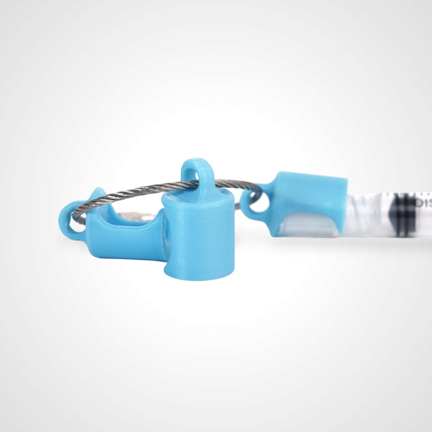 Three blue polylactic acid created using additive manufacturing classic cap clips on steel cable keyring. Featured attached to a syringe. Shown on a white background.