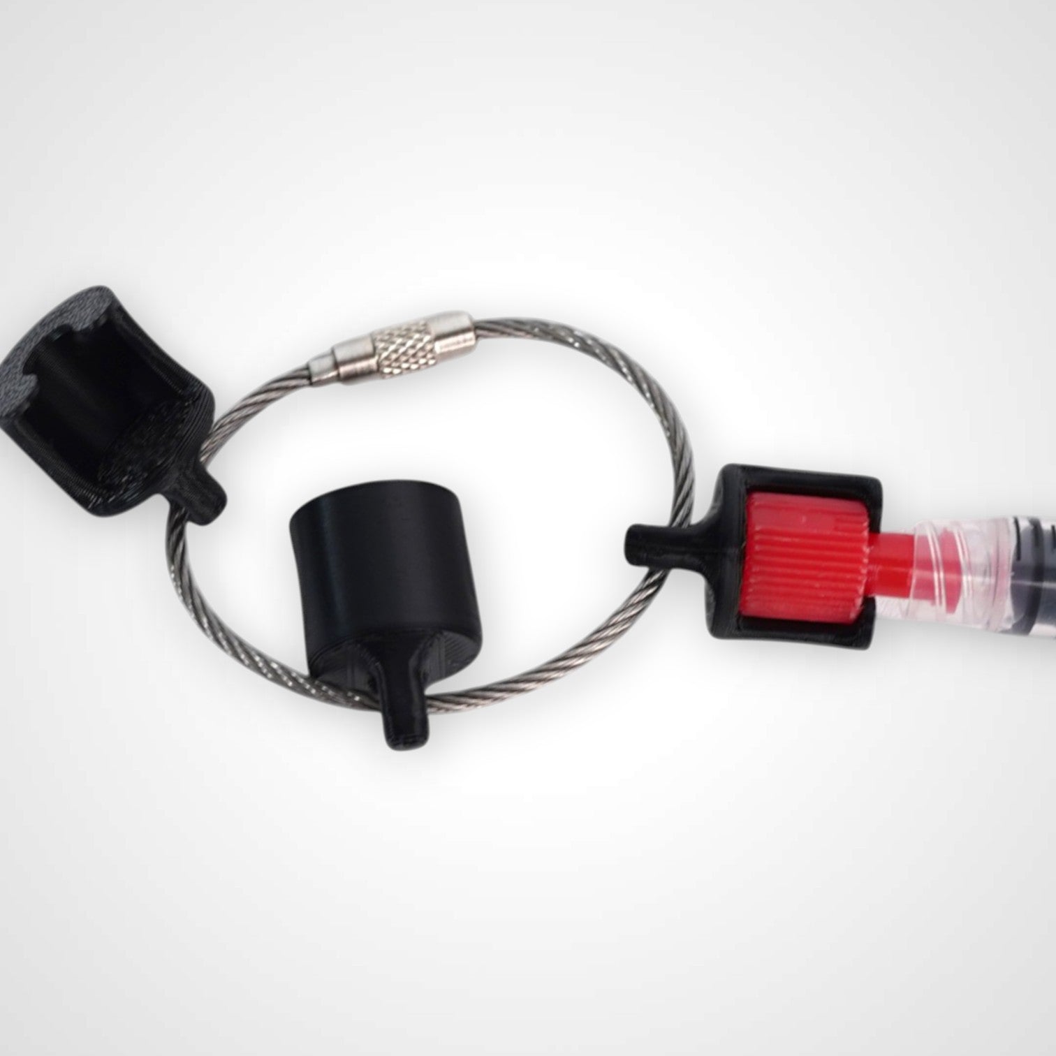Black polylactic acid created using additive manufacturing B-Braun cap clip on steel cable keyring. Featured attached to a syringe. Shown on white background.