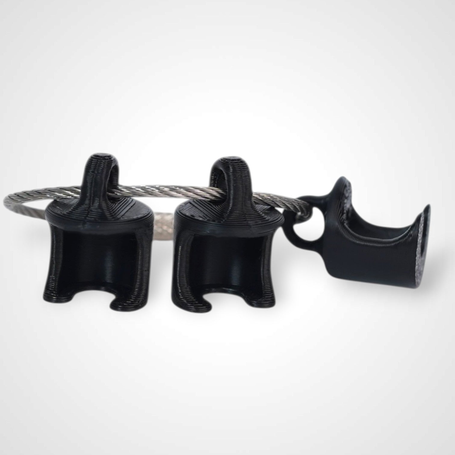 Black polylactic acid created using additive manufacturing B-Braun cap clip on steel cable keyring. Shown on white background.