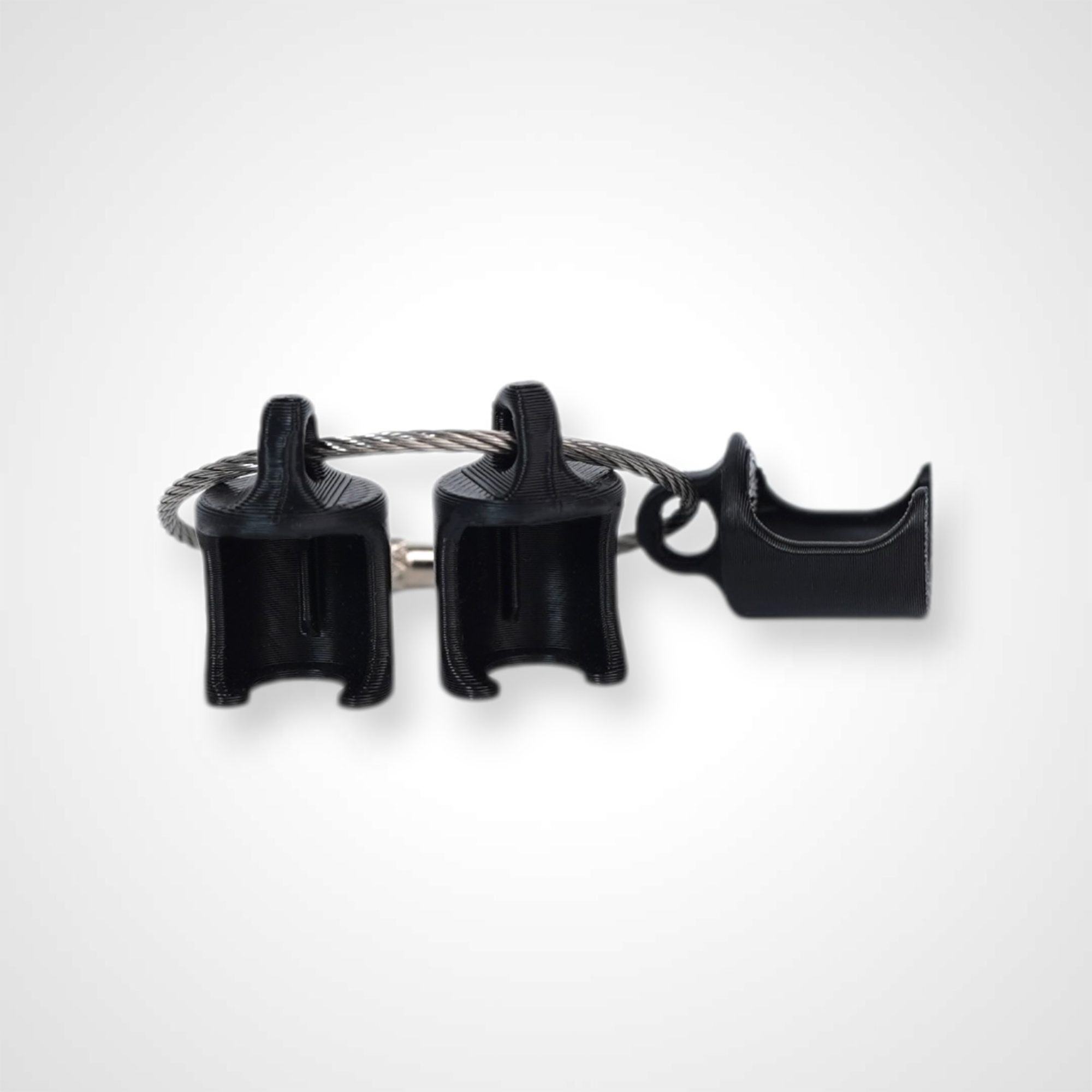Three black polylactic acid created using additive manufacturing classic cap clips on steel cable keyring. Shown on a white background.