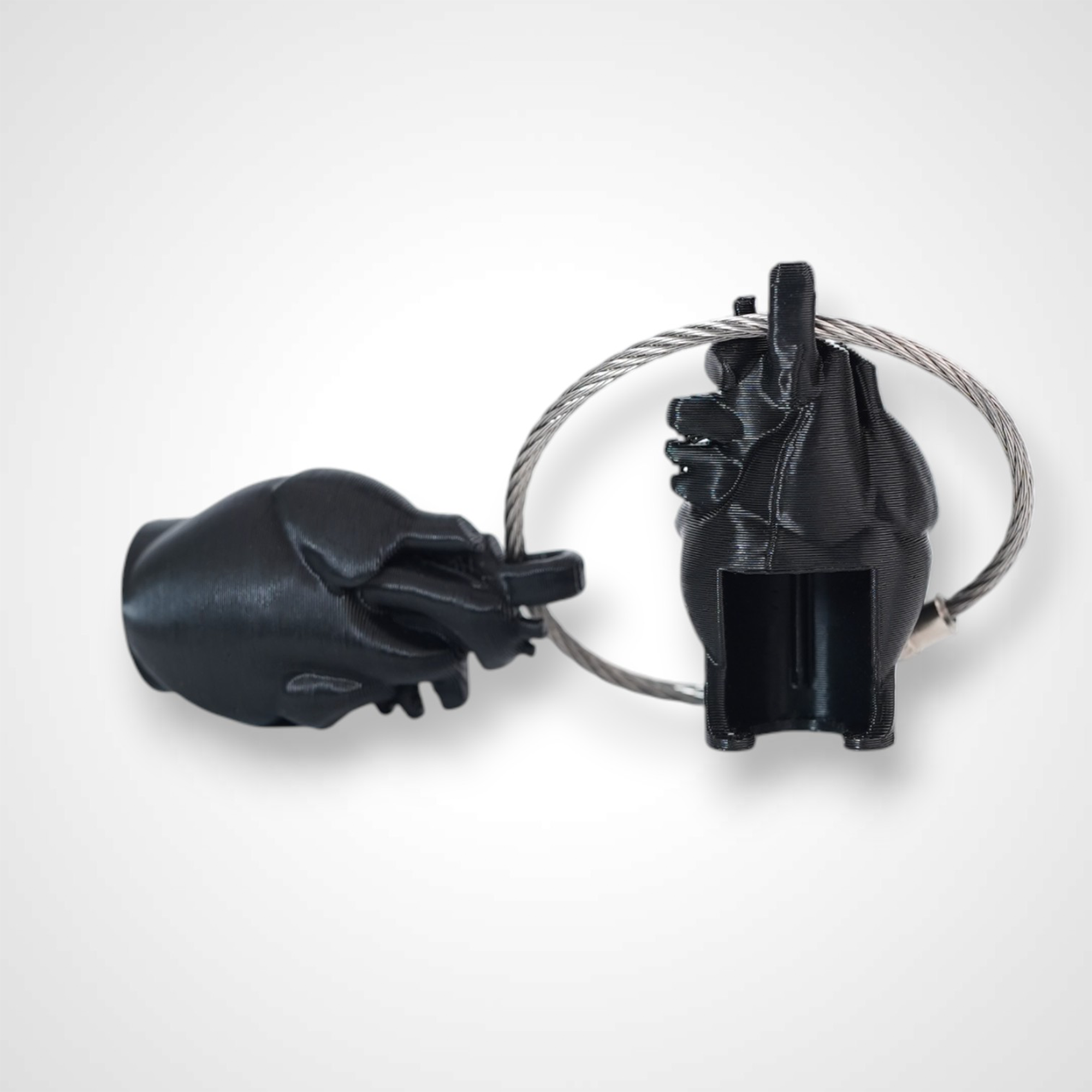 Two black polylactic acid created using additive manufacturing anatomical heart cap clips on steel cable keyring. Shown on a white background.