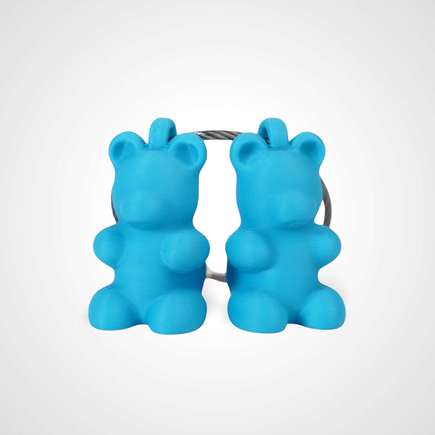 Two blue polylactic acid created using additive manufacturing gummy bear clips on steel cable keyring. Shown on a white background.