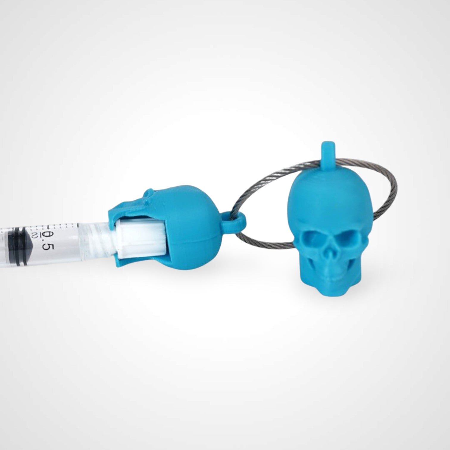 Two blue polylactic acid created using additive manufacturing skull cap clips on steel cable keyring. Featured attached to a syringe. Shown on a white background.