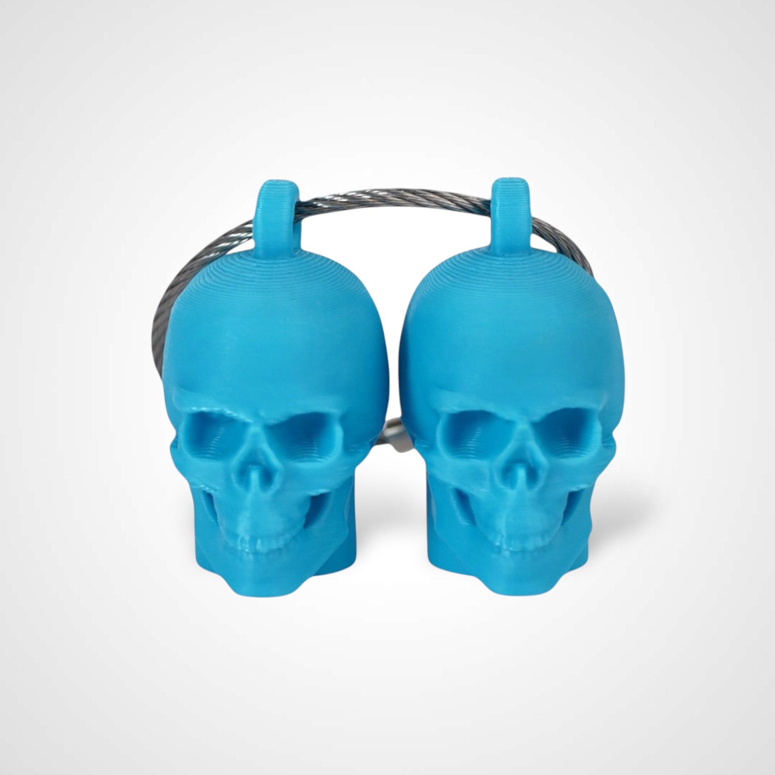 Two blue polylactic acid created using additive manufacturing skull cap clips on steel cable keyring. Shown on a white background.