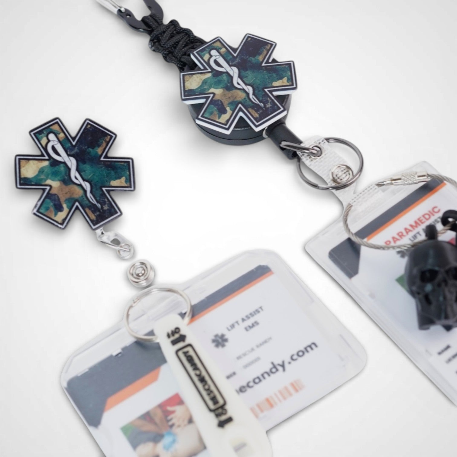 Camo Star badge reel. On a carabiner with a steel retractable cable next to a swivel-alligator clip that rotates 360° with a nylon retractable string. Shown on a white background.