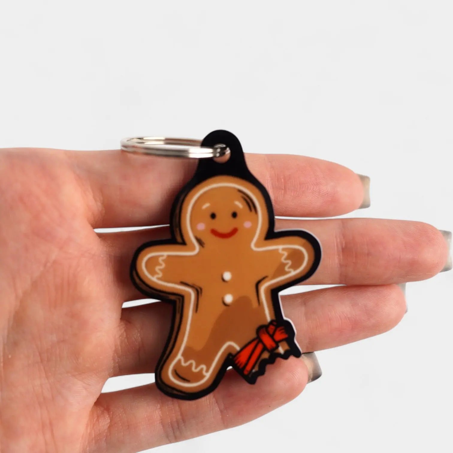 Tourniquet gingerbread man cast acrylic keychain with double coil keyring. Shown being held.