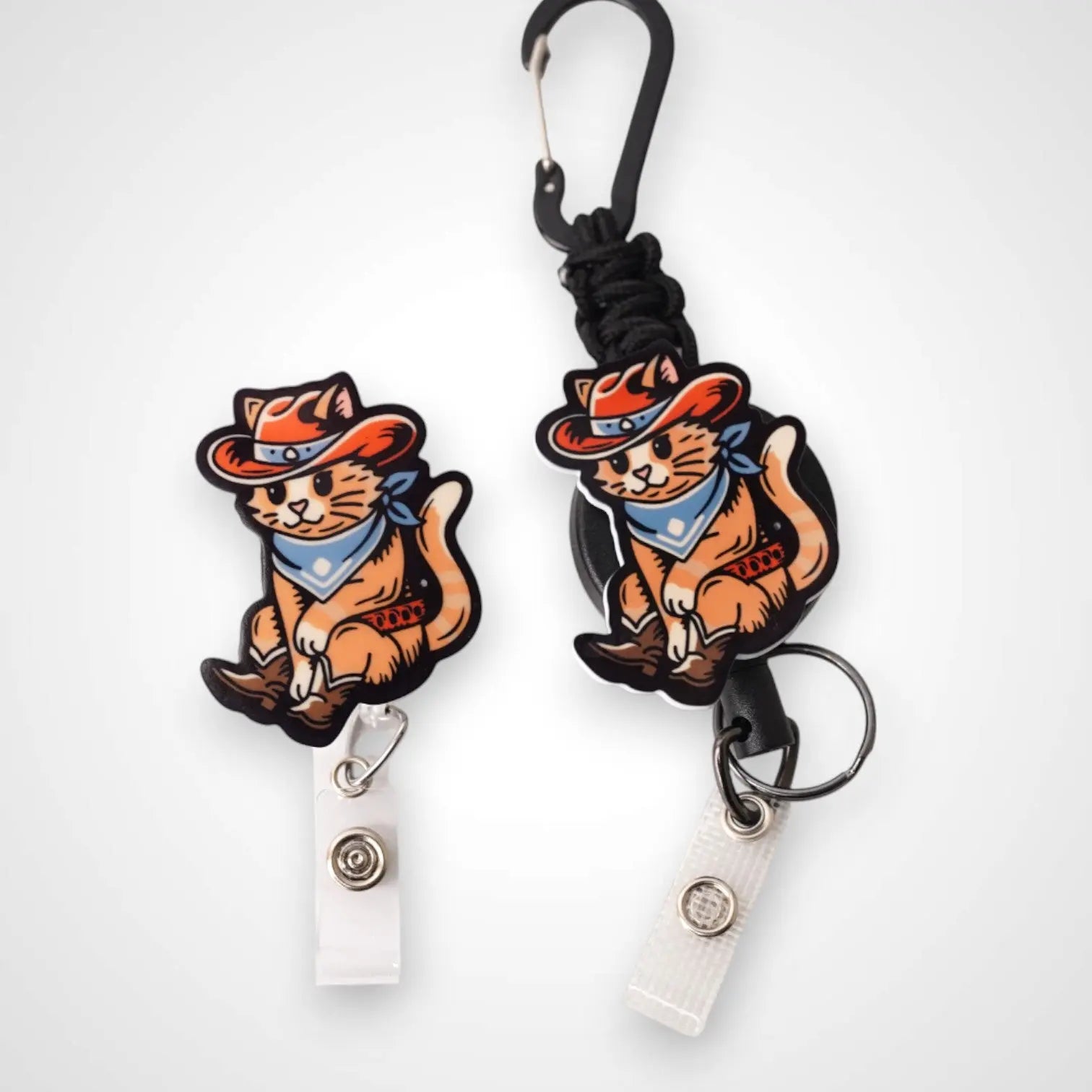 Cowboy Cat badge reel. On a carabiner with a steel retractable cable next to a swivel-alligator clip that rotates 360° with a nylon retractable string. Shown on a white background.