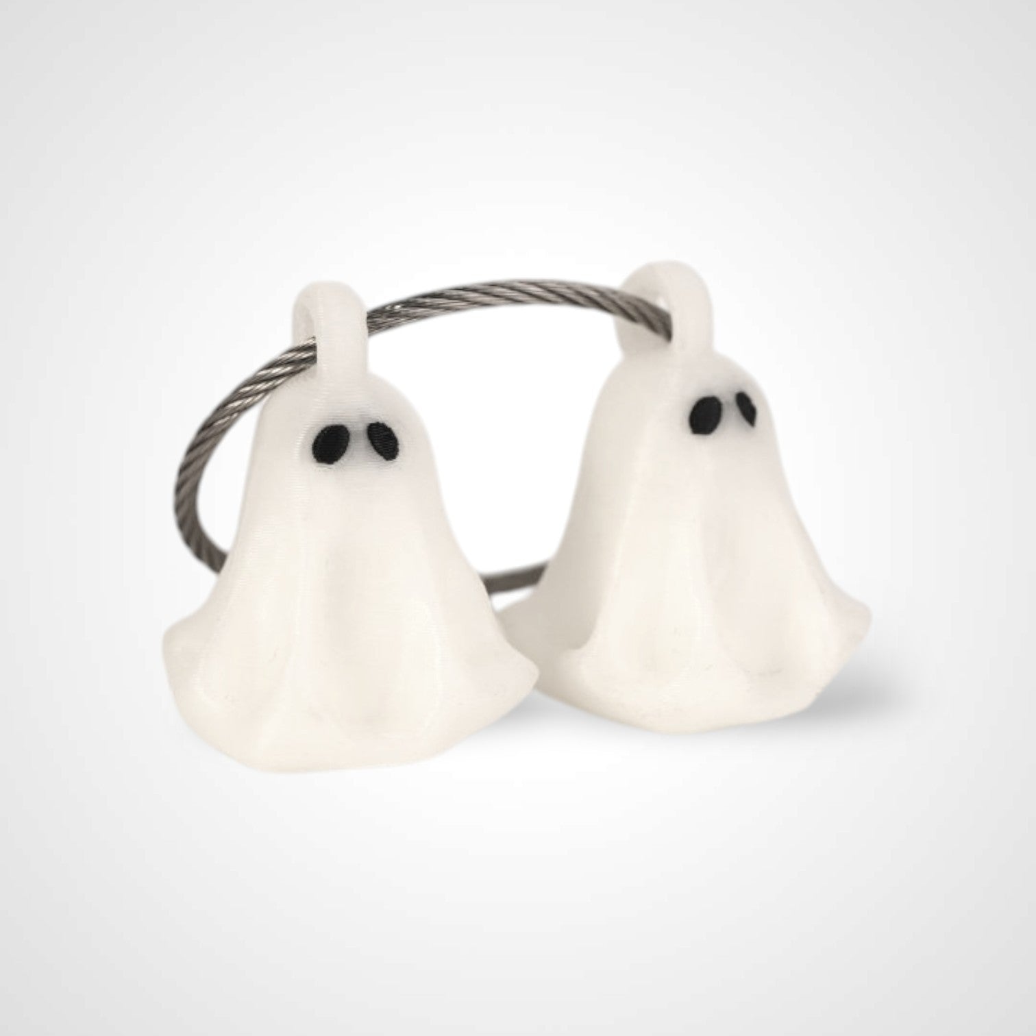 Two white polylactic acid created using additive manufacturing ghost cap clips on steel cable keyring. Shown on a white background.