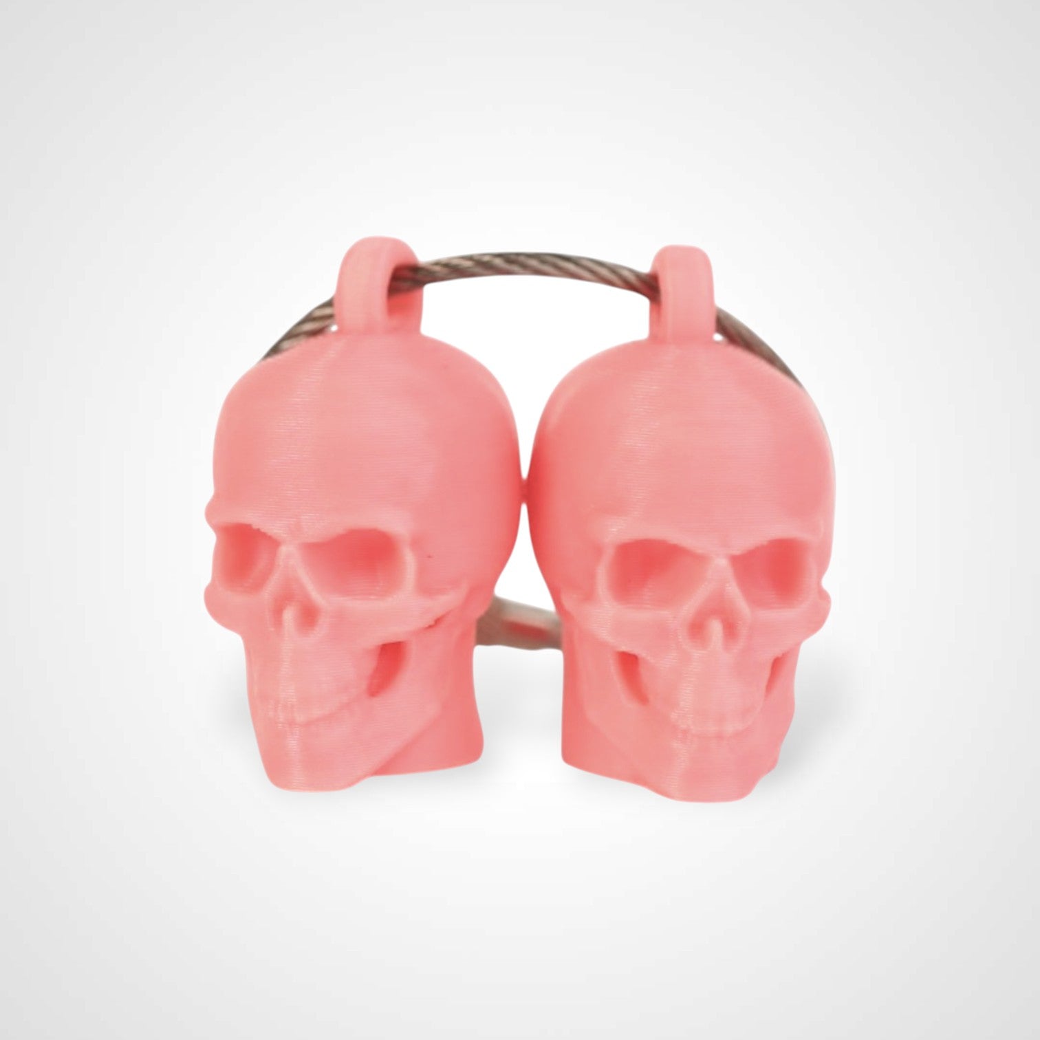 Two pink polylactic acid created using additive manufacturing skull cap clips on steel cable keyring. Shown on a white background.