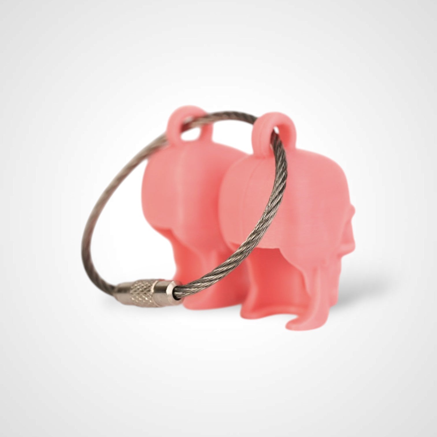 Two pink polylactic acid created using additive manufacturing skull cap clips on steel cable keyring. Shown on a white background.