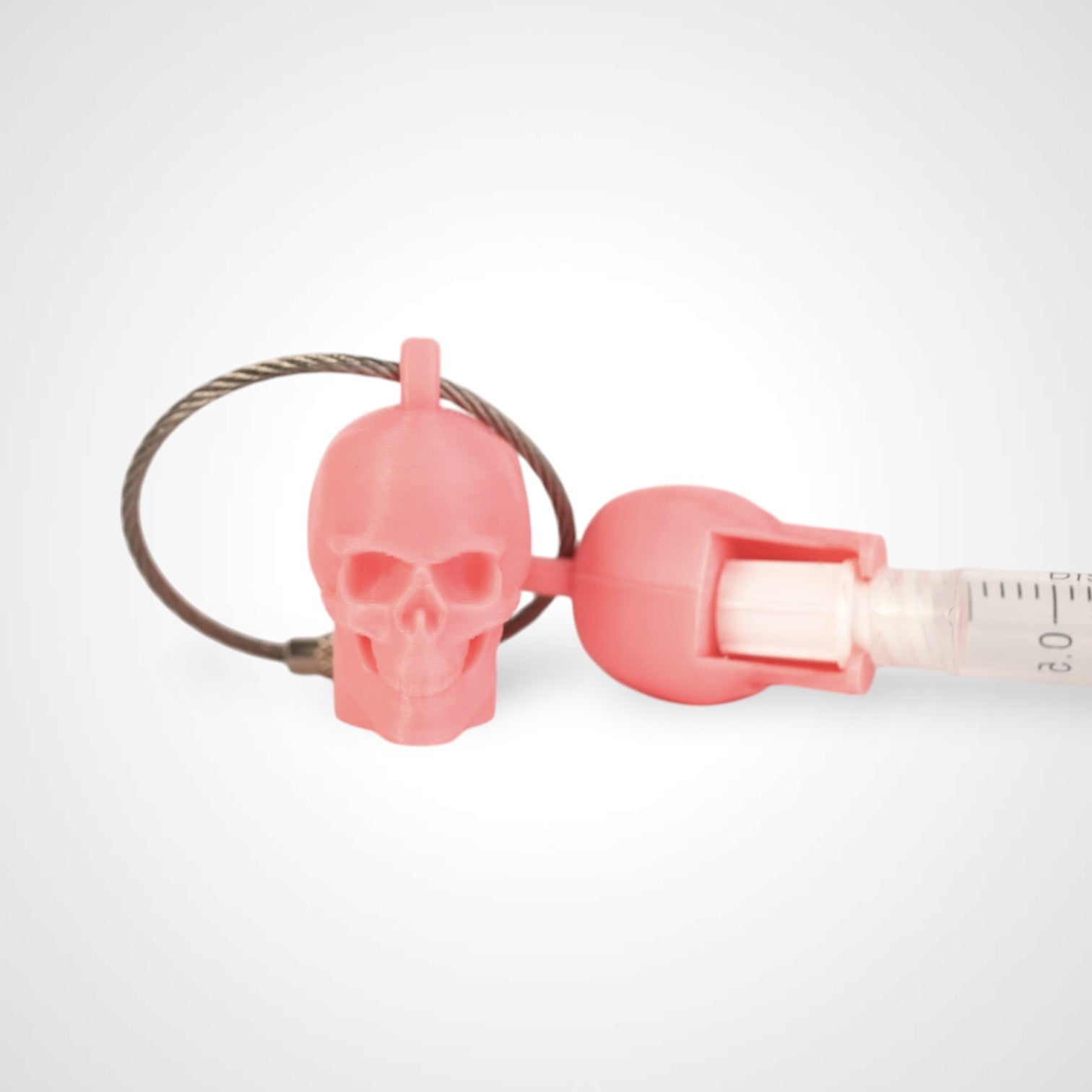 Two pink polylactic acid created using additive manufacturing skull cap clips on steel cable keyring. Featured attached to a syringe. Shown on a white background.