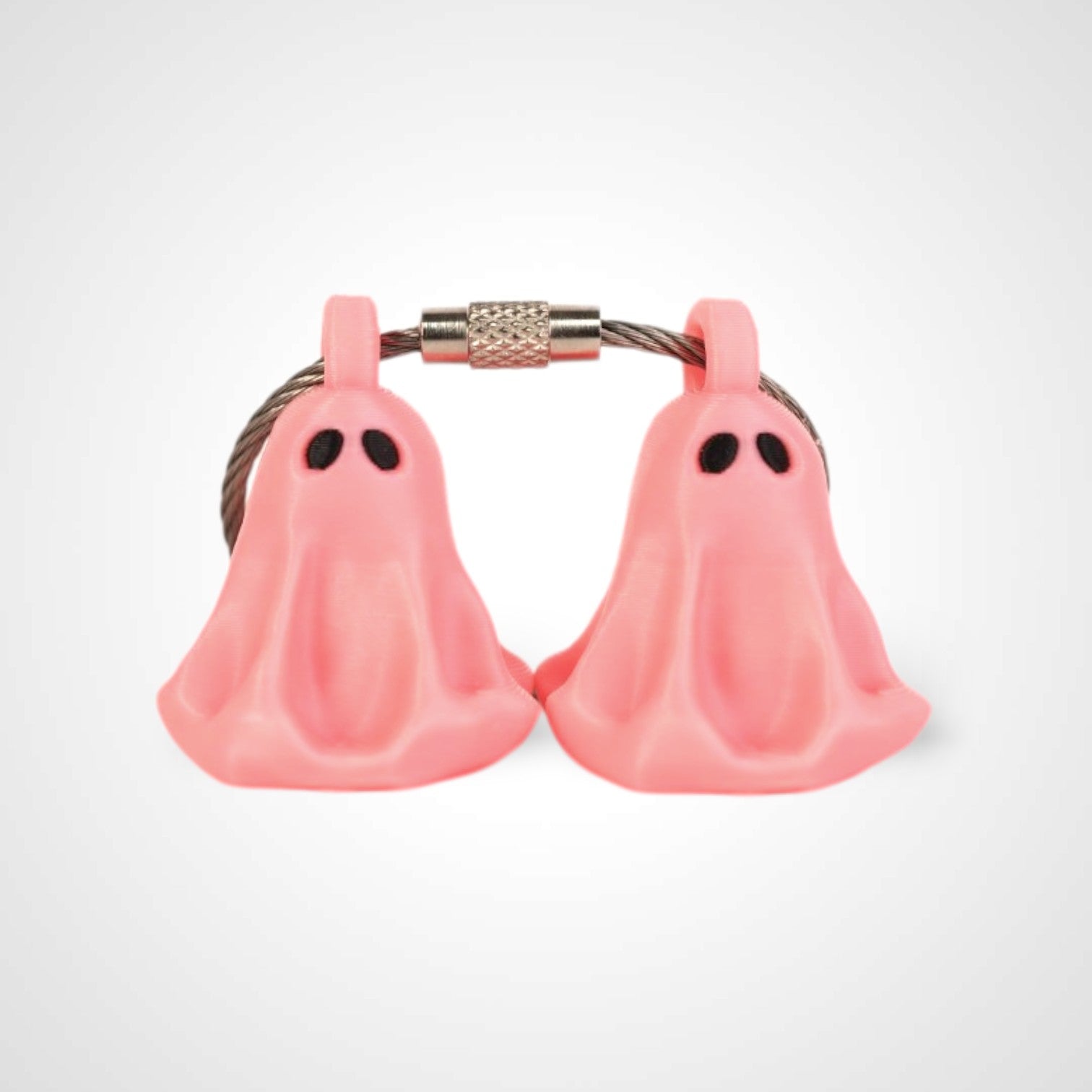 Two pink polylactic acid created using additive manufacturing ghost cap clips on steel cable keyring. Shown on a white background.