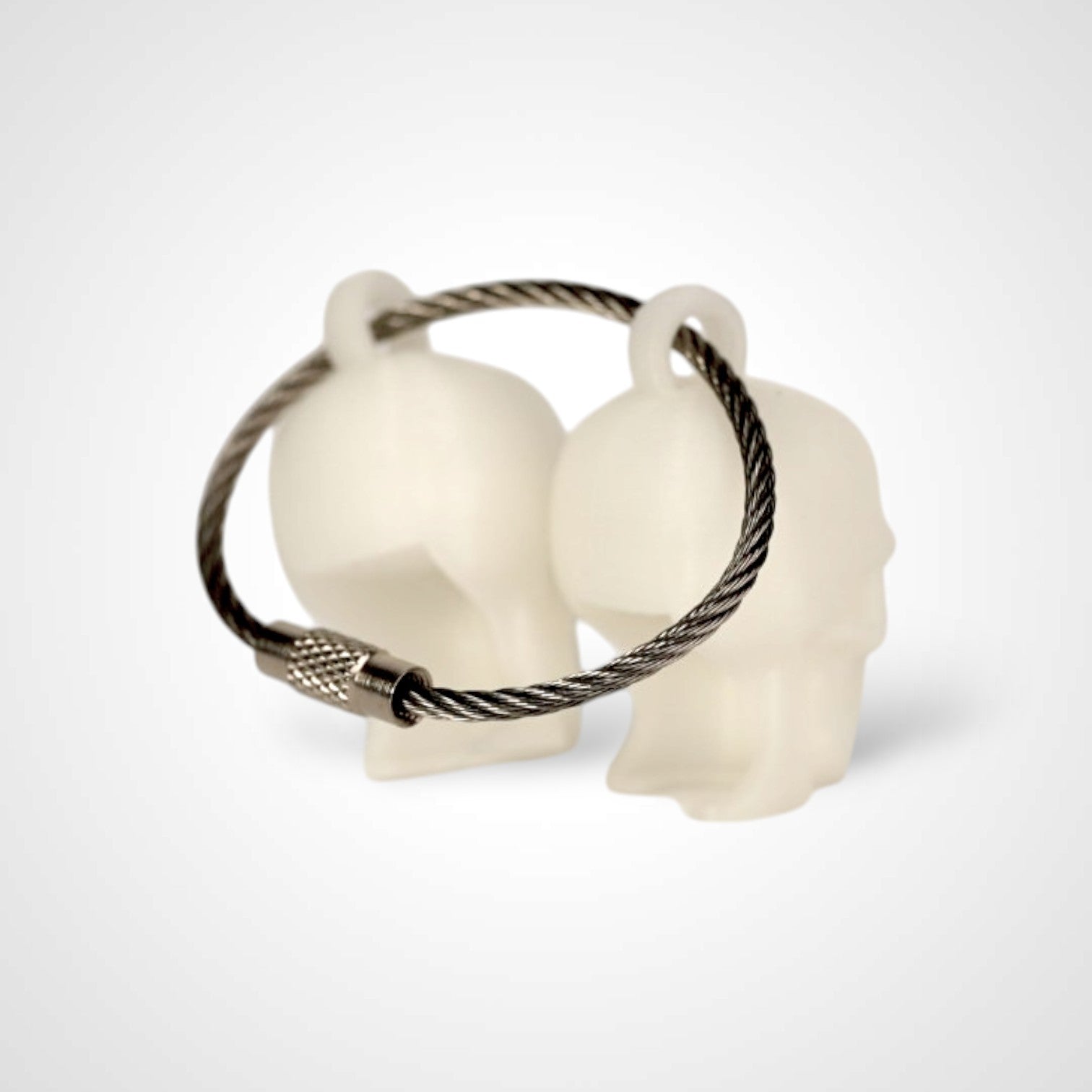 Two white polylactic acid created using additive manufacturing skull cap clips on steel cable keyring. Shown on a white background.
