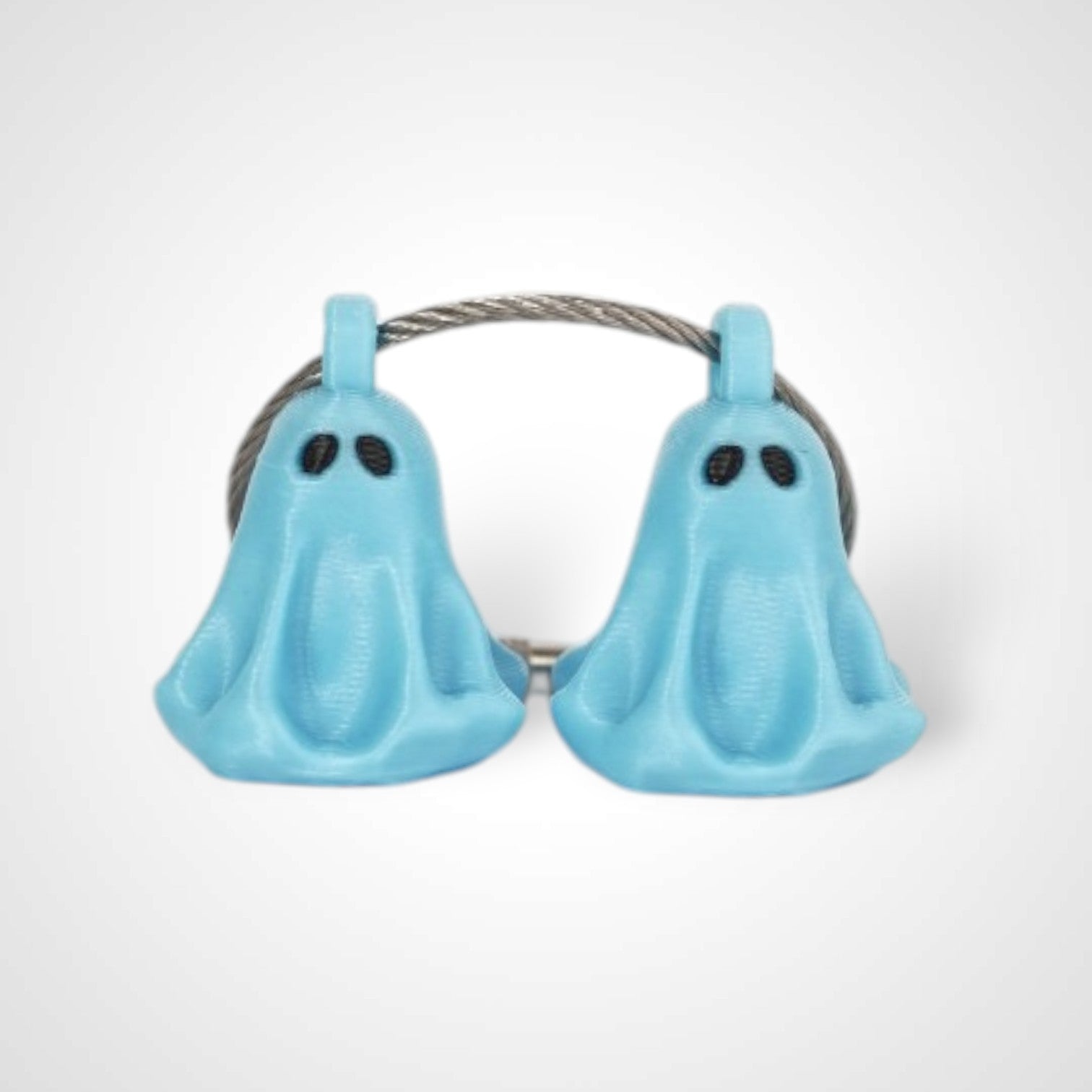 Two blue polylactic acid created using additive manufacturing ghost cap clips on steel cable keyring. Shown on a white background.