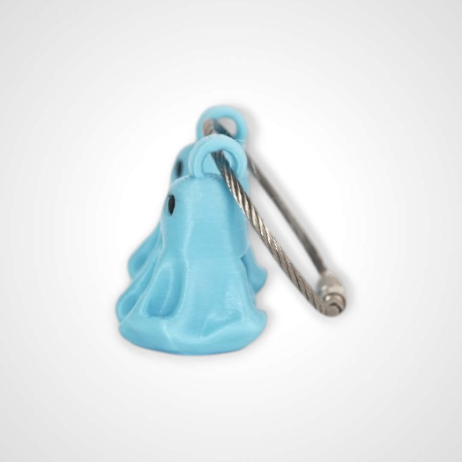 Two blue polylactic acid created using additive manufacturing ghost cap clips on steel cable keyring. Shown on a white background.