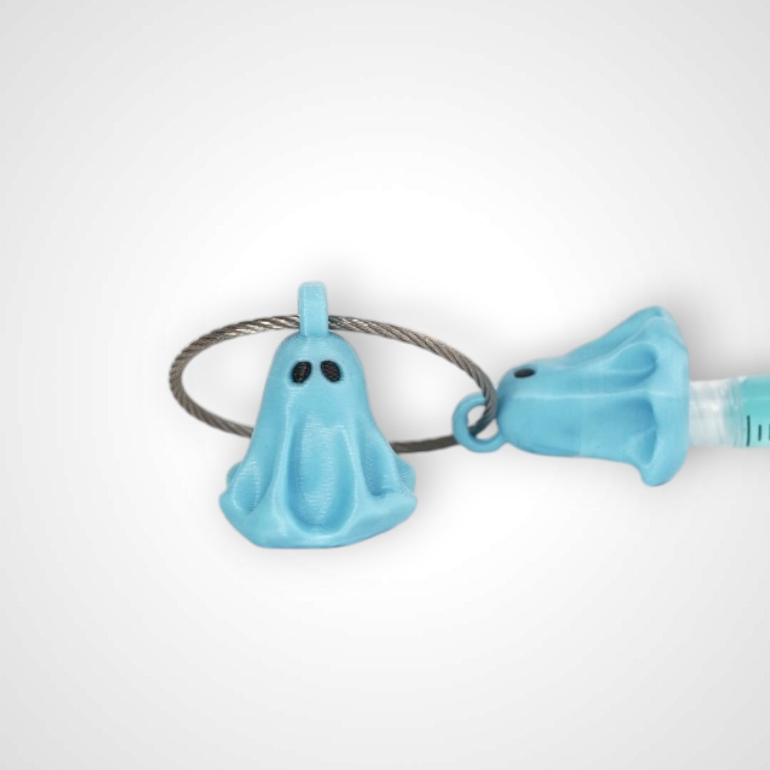 Two blue polylactic acid created using additive manufacturing ghost cap clips on steel cable keyring. Shown on a white background.