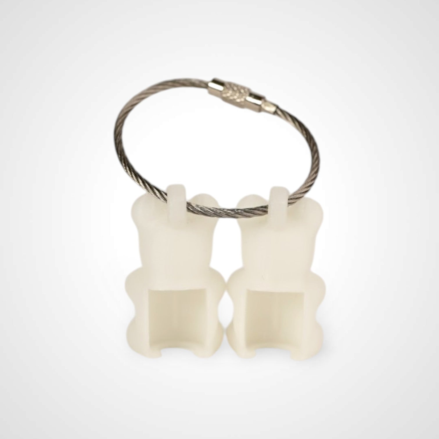 Two white polylactic acid created using additive manufacturing gummy bear cap clips on steel cable keyring. Shown on a white background.