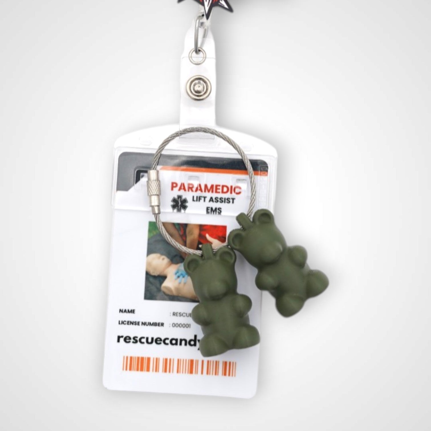 Two army green polylactic acid created using additive manufacturing gummy bear clips on steel cable keyring. Featured attached to a badge. Shown on a white background.