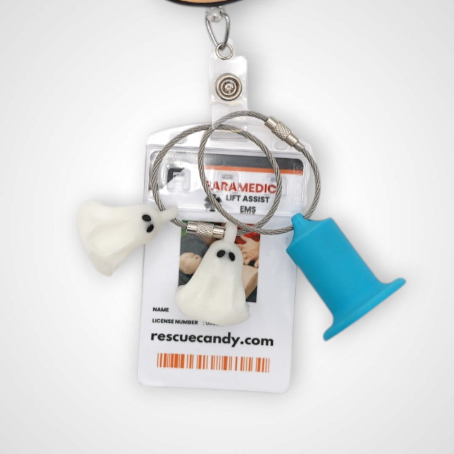 Two white polylactic acid created using additive manufacturing ghost cap clips on steel cable keyring. Featured attached to a badge. Shown on a white background.