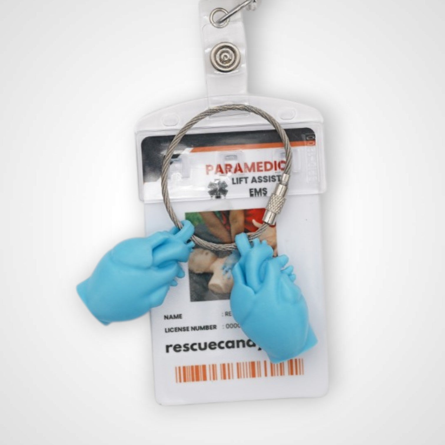 Two blue polylactic acid created using additive manufacturing anatomical heart cap clip on steel cable keyring. Featured attached to a badge. Shown on white background.