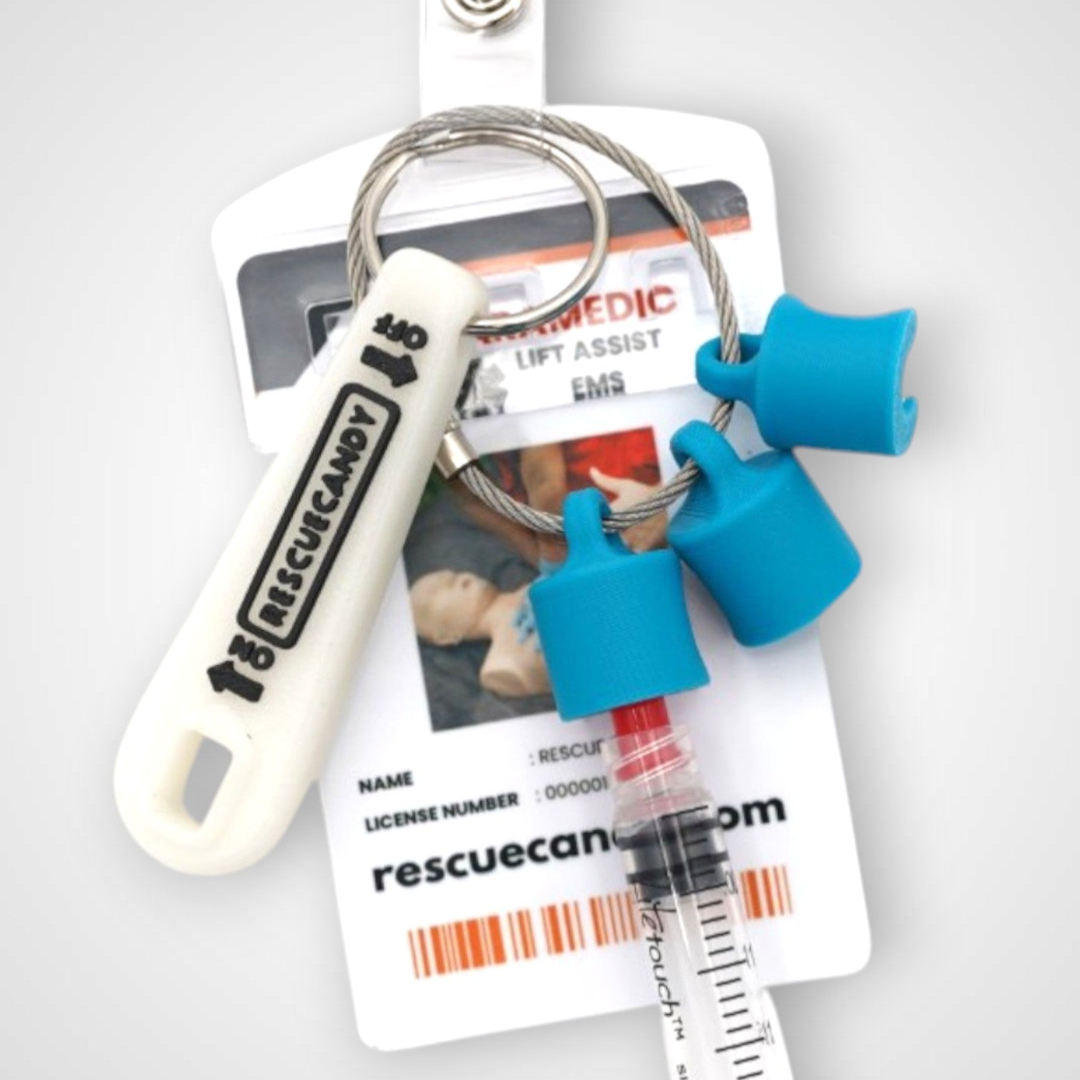 Blue polylactic acid created using additive manufacturing B-Braun cap clip on steel cable keyring. Featured attached to a syringe and on a badge. Shown on white background.
