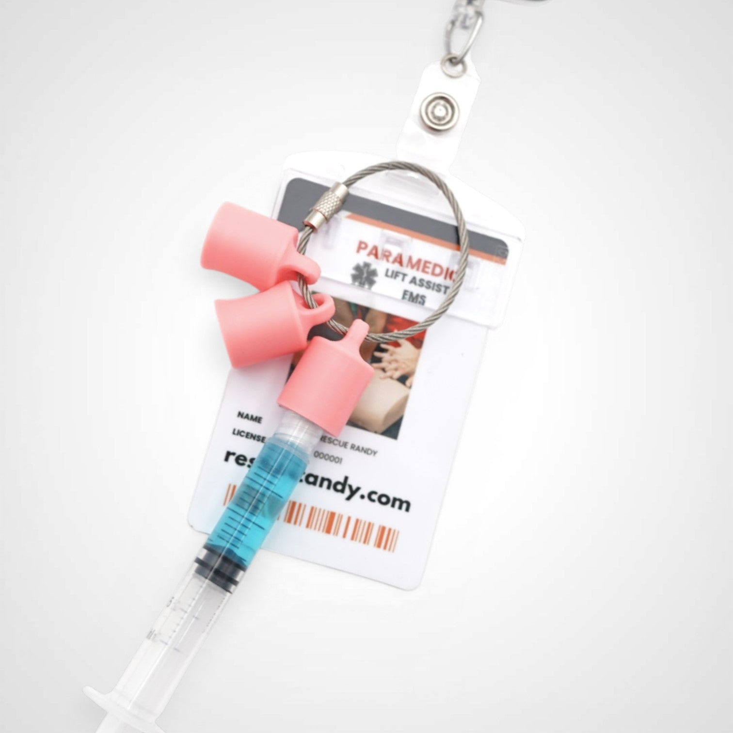 Three pink polylactic acid created using additive manufacturing classic cap clips on steel cable keyring. Featured attached to a syringe and on a badge. Shown on a white background.