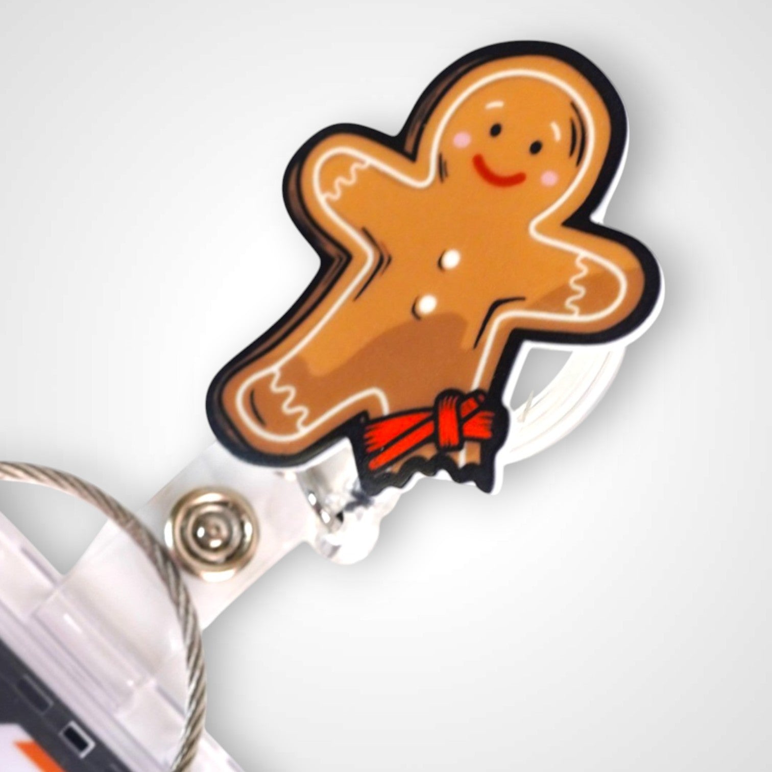 Tourniquet gingerbread man badge reel. On a swivel-alligator clip that rotates 360° with a nylon retractable string. Shown on a white background.
