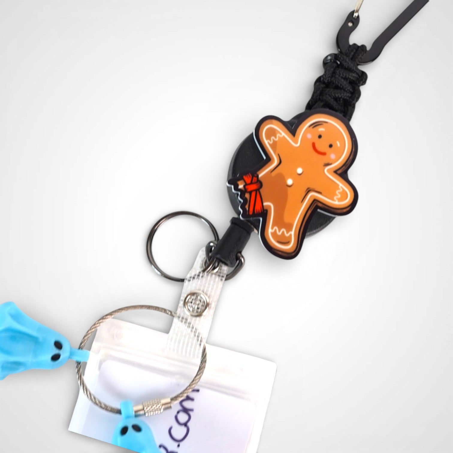 Tourniquet gingerbread man badge reel. On a carabiner with a steel retractable cable. Shown on a white background.