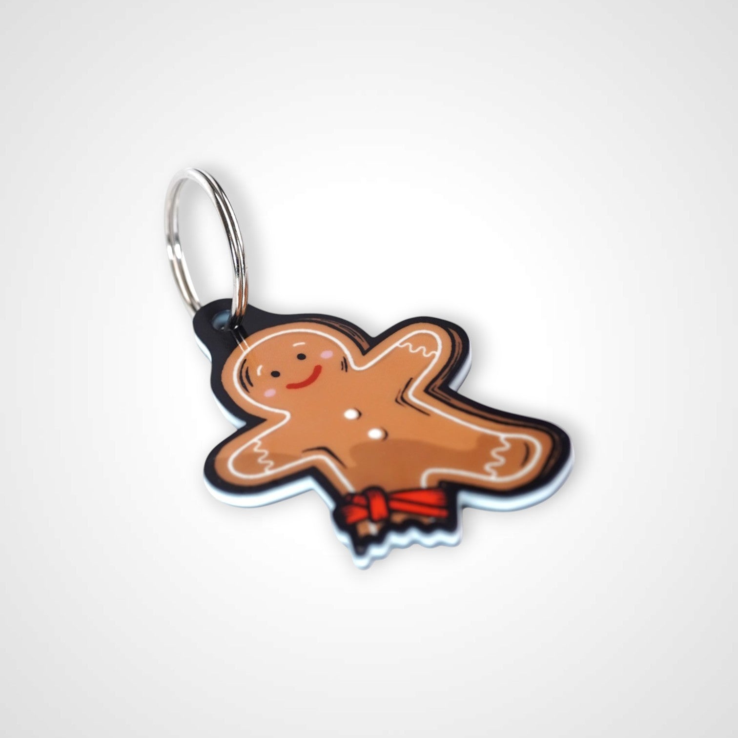 Tourniquet gingerbread man cast acrylic keychain with double coil keyring. Shown on white background.
