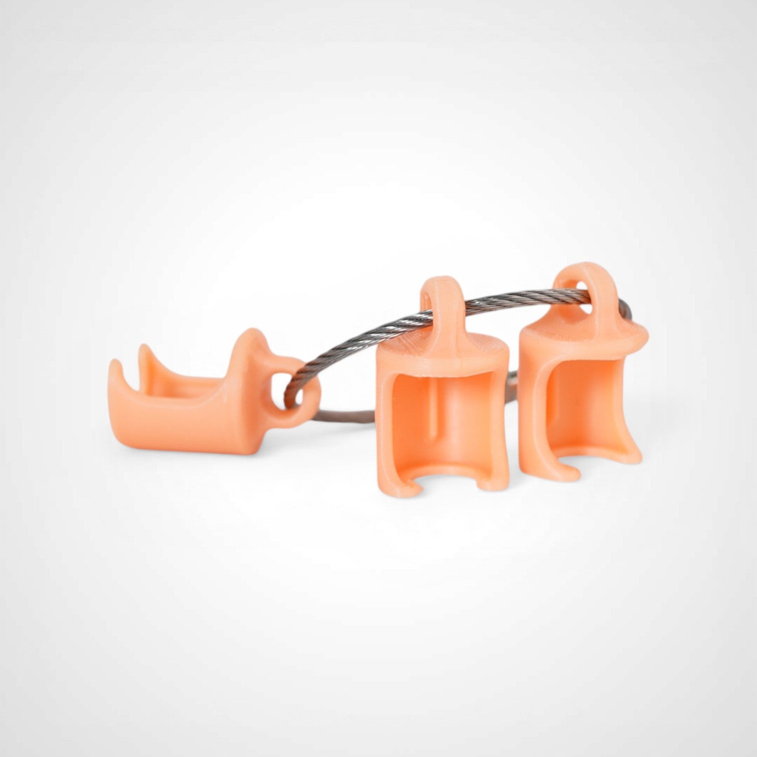 Three orange polylactic acid created using additive manufacturing classic cap clips on steel cable keyring. Shown on a white background.