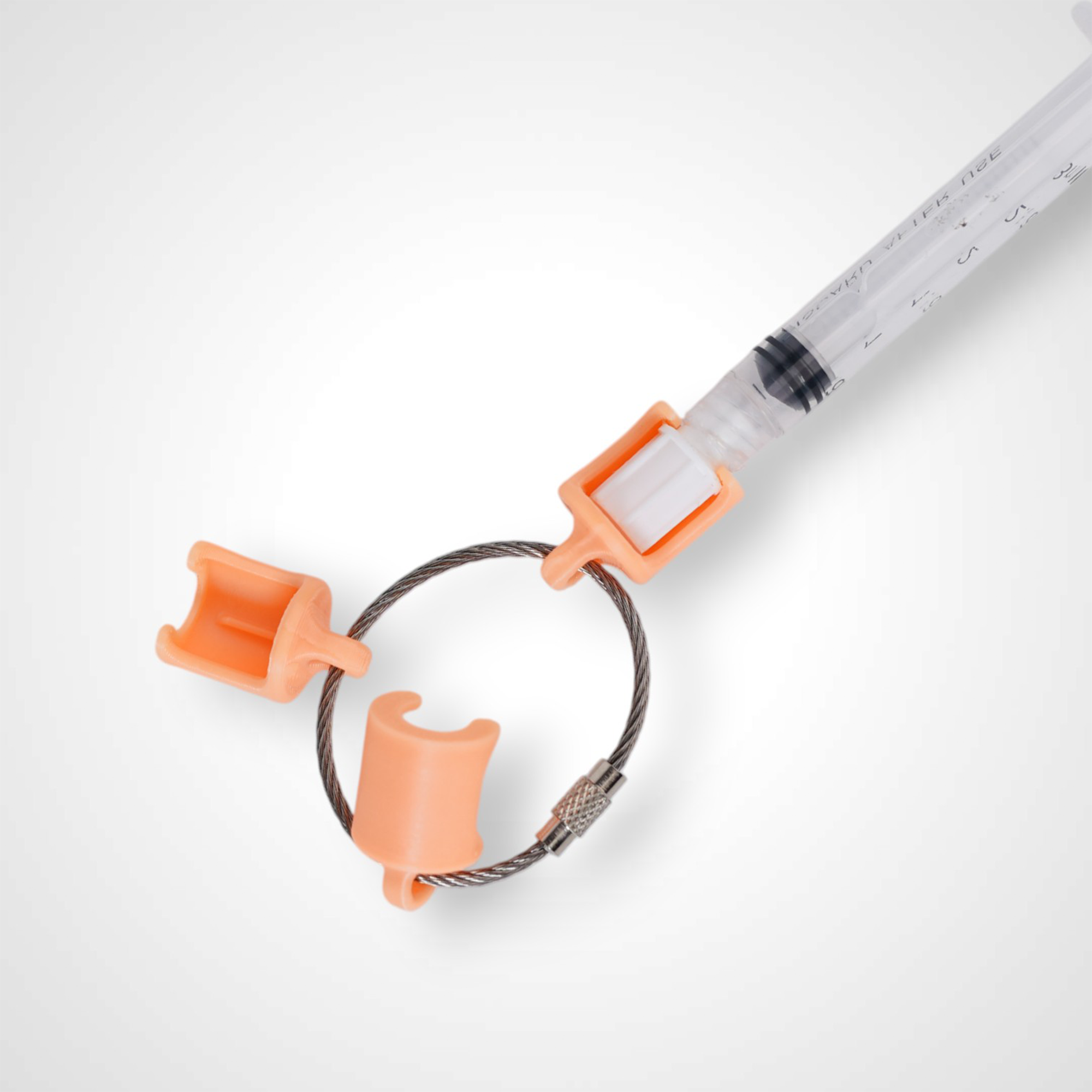 Three orange polylactic acid created using additive manufacturing classic cap clips on steel cable keyring. Featured attached to a syringe. Shown on a white background.