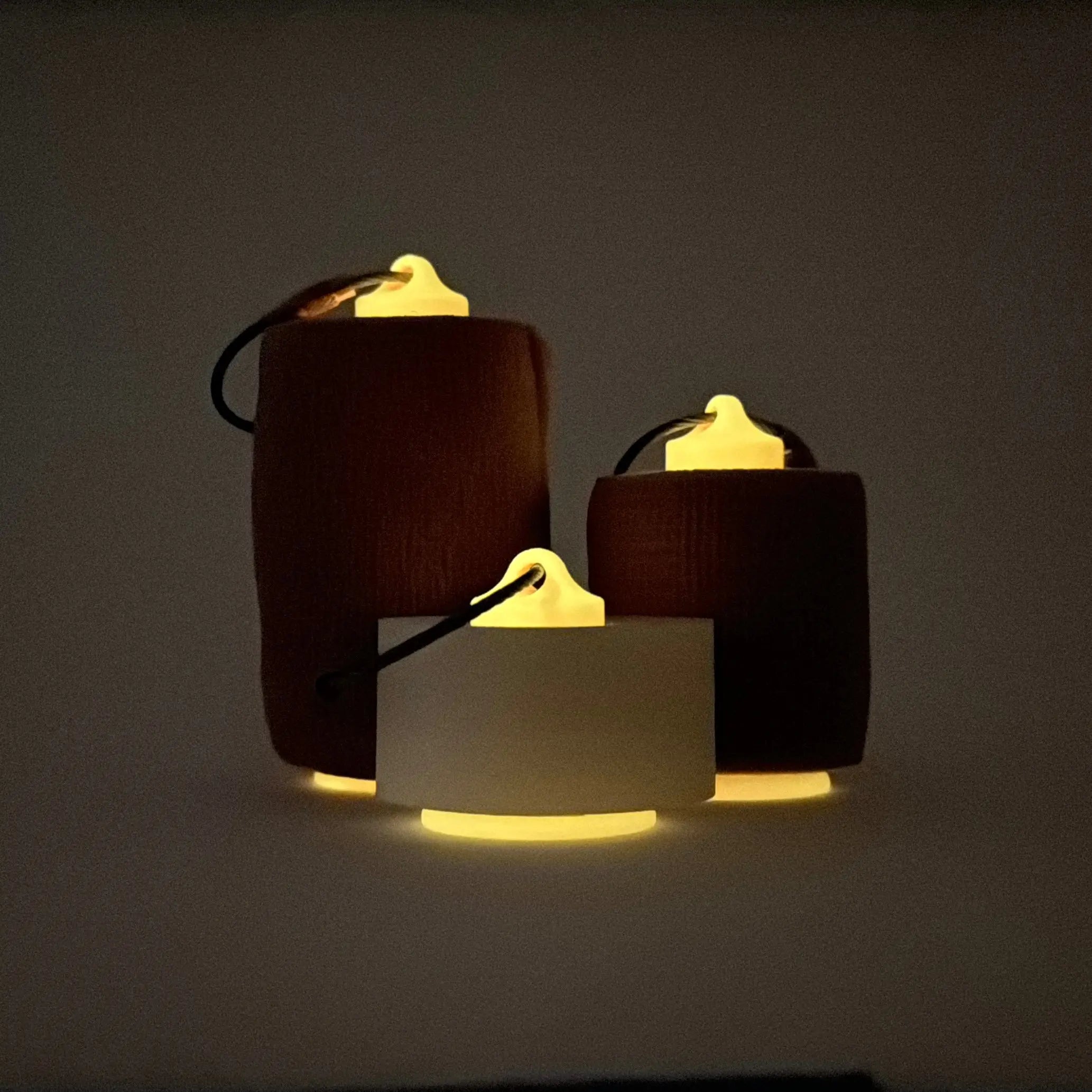 Pink glow orange roll holders made with polylactic acid, created using additive manufacturing for holding tape and bandage rolls. In three sizes, 1-inch, 2-inch, and 3-inch. With a steel cable keyring. All three sizes shown, with tape on them, glowing on black backgorund.