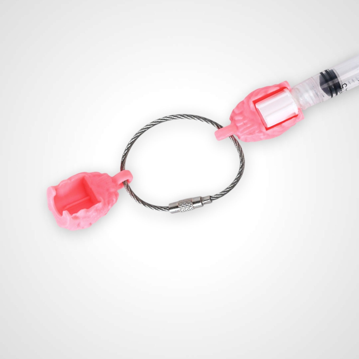 Two pink polylactic acid created using additive manufacturing anatomical brain cap clips on steel cable keyring. Featured attached to a syringe. Shown on a white background.