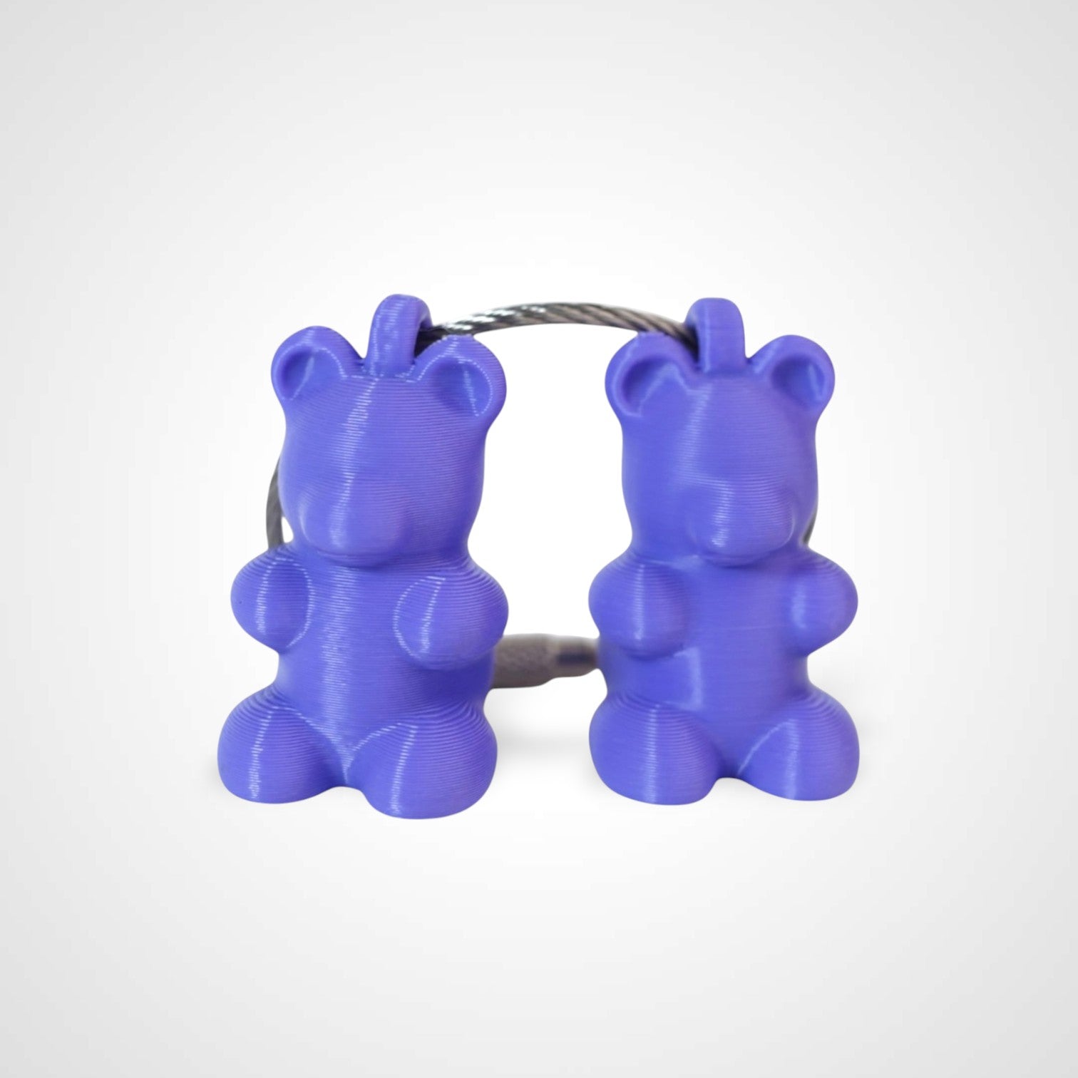 Two purple polylactic acid created using additive manufacturing gummy bear clips on steel cable keyring. Shown on a white background.