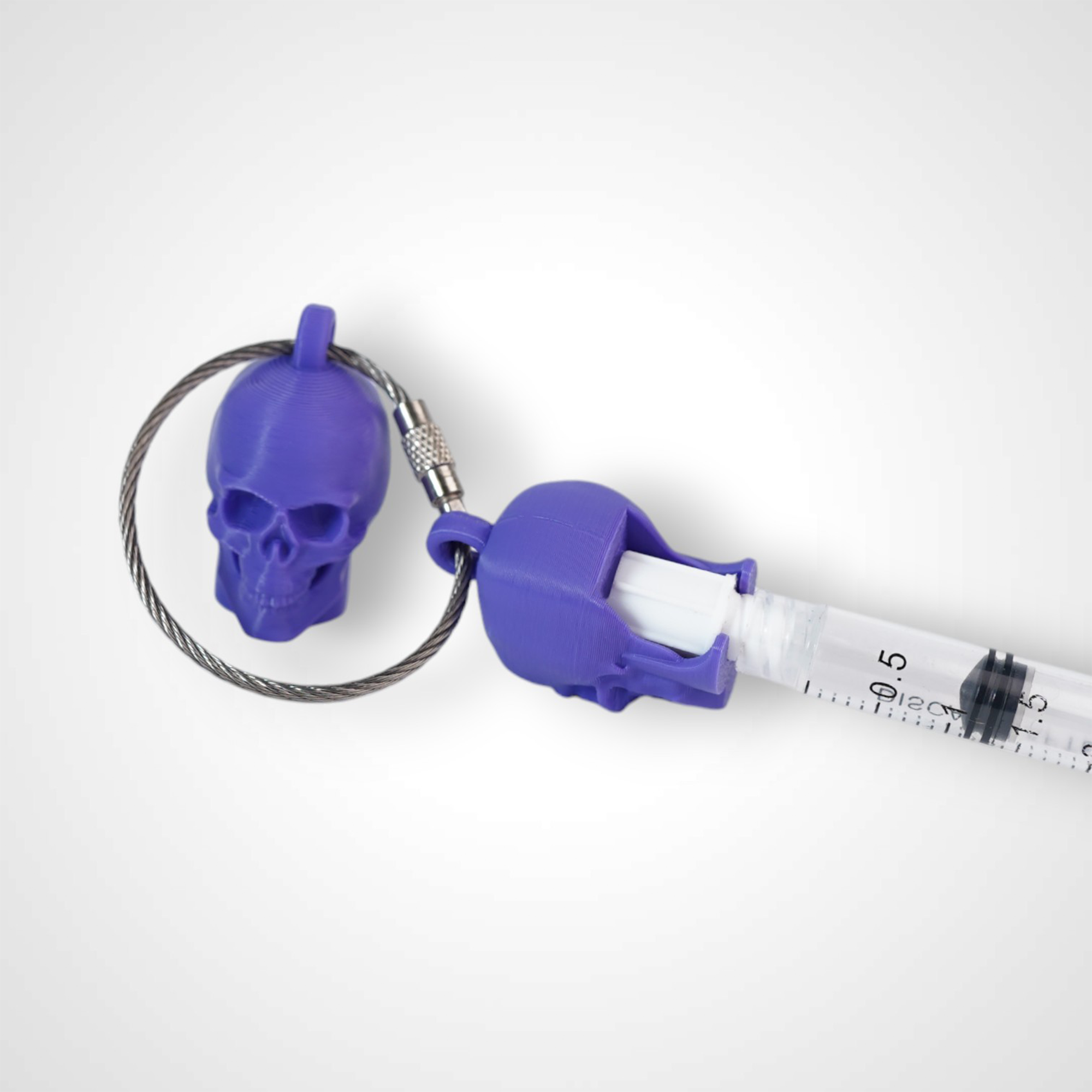 Two purple polylactic acid created using additive manufacturing skull cap clips on steel cable keyring. Featured attached to a syringe. Shown on a white background.