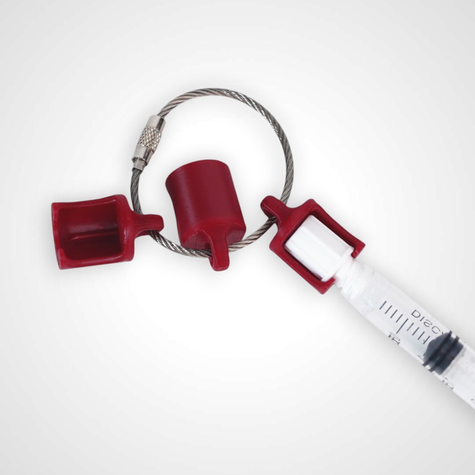 Three red polylactic acid created using additive manufacturing classic cap clip on steel cable keyring. Featured attached to syringe. Shown on white background.