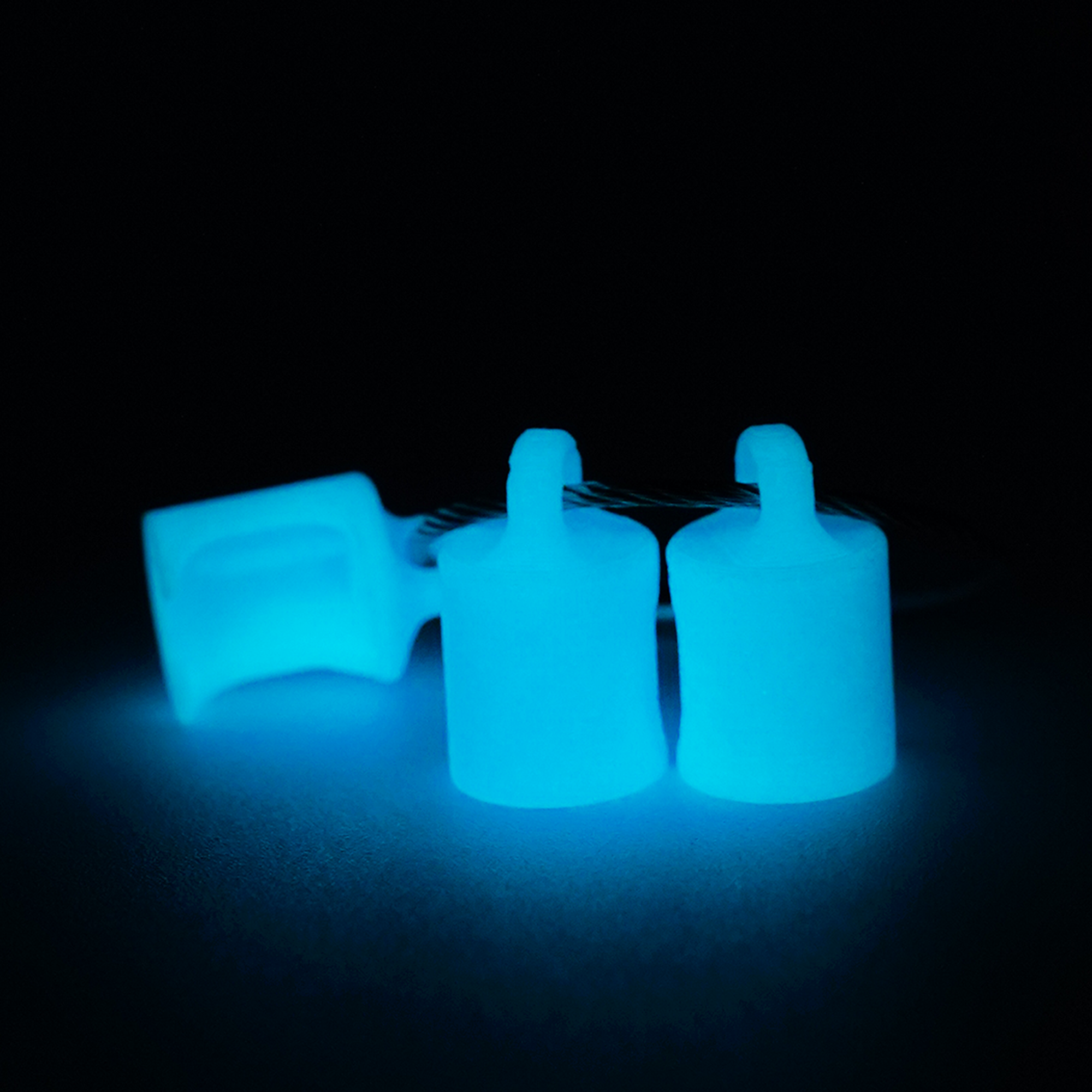 Three blue polylactic acid created using additive manufacturing classic cap clips on steel cable keyring. Shown glowing blue on a black background.