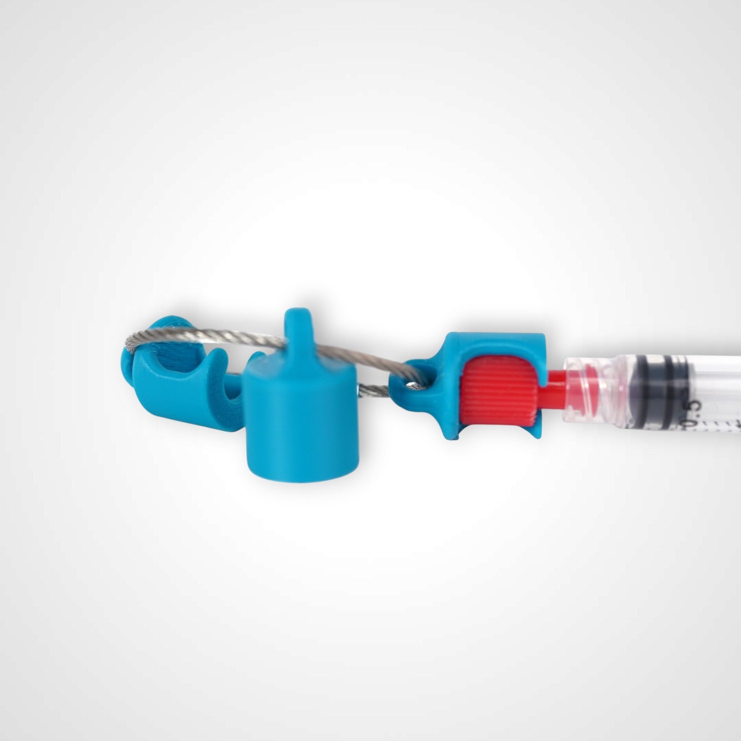 Blue polylactic acid created using additive manufacturing B-Braun cap clip on steel cable keyring. Featured attached to syringe. Shown on white background.