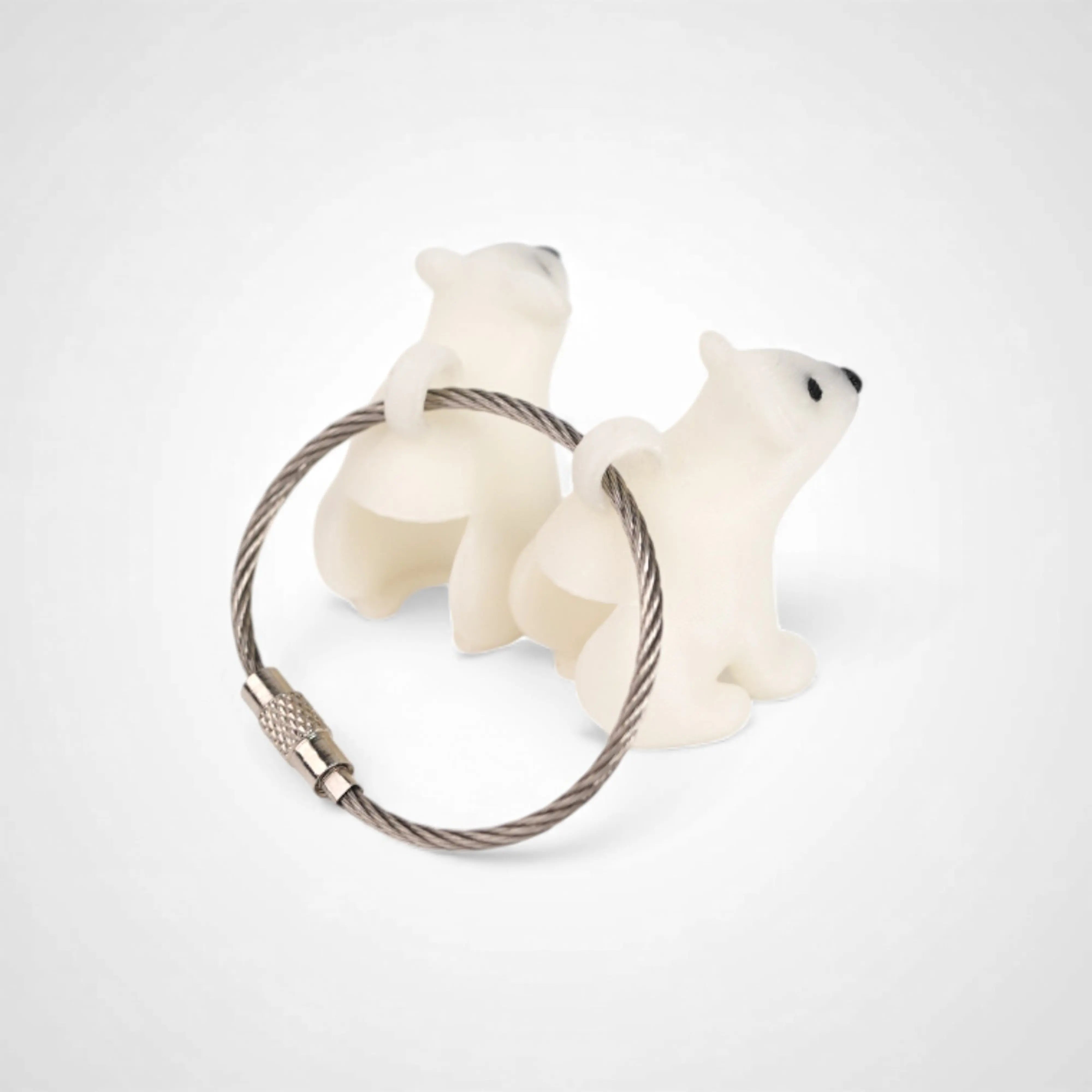 Two white polylactic acid created using additive manufacturing polar bear cap clips on steel cable keyring. Shown on a white background.