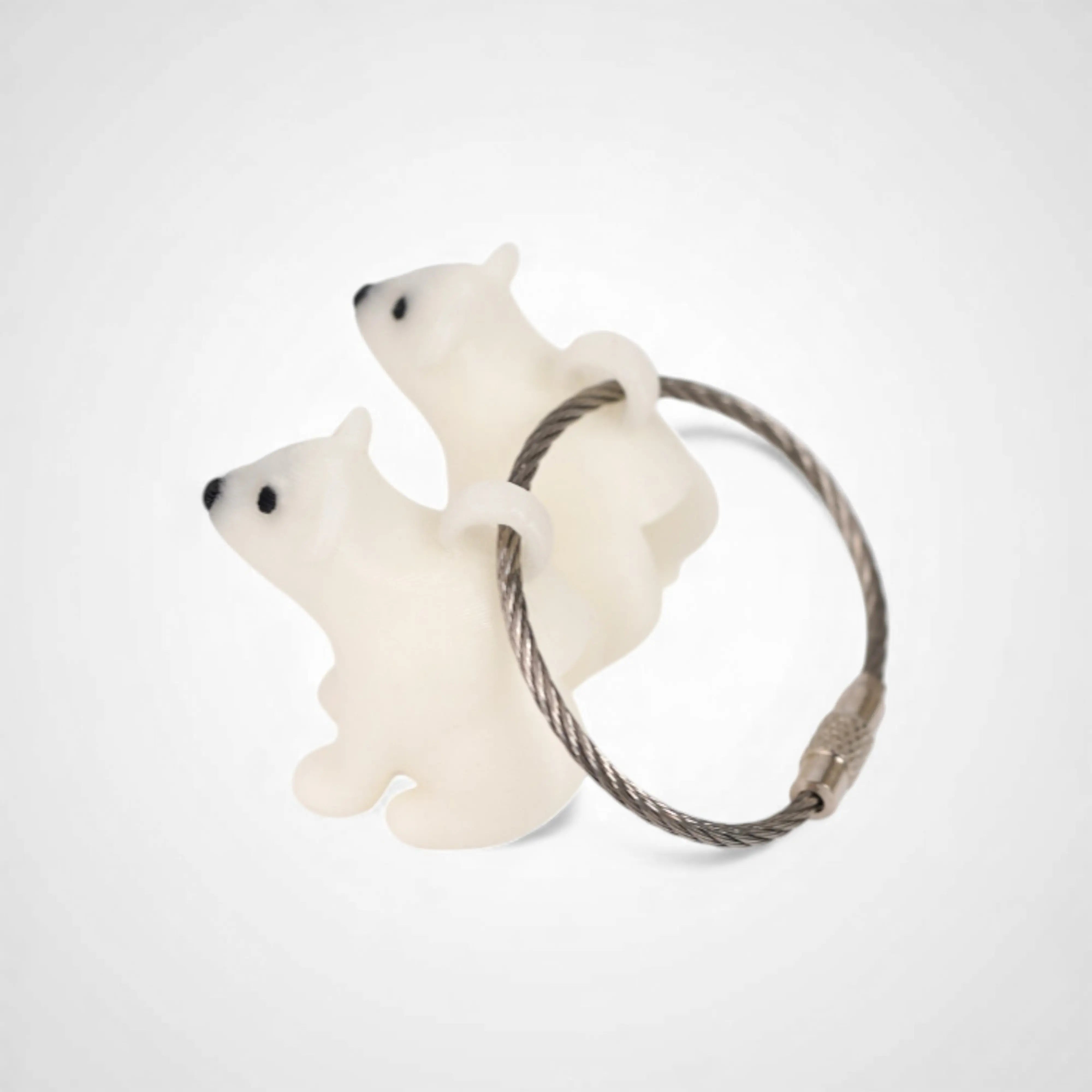 Two white polylactic acid created using additive manufacturing polar bear cap clips on steel cable keyring. Shown on a white background.