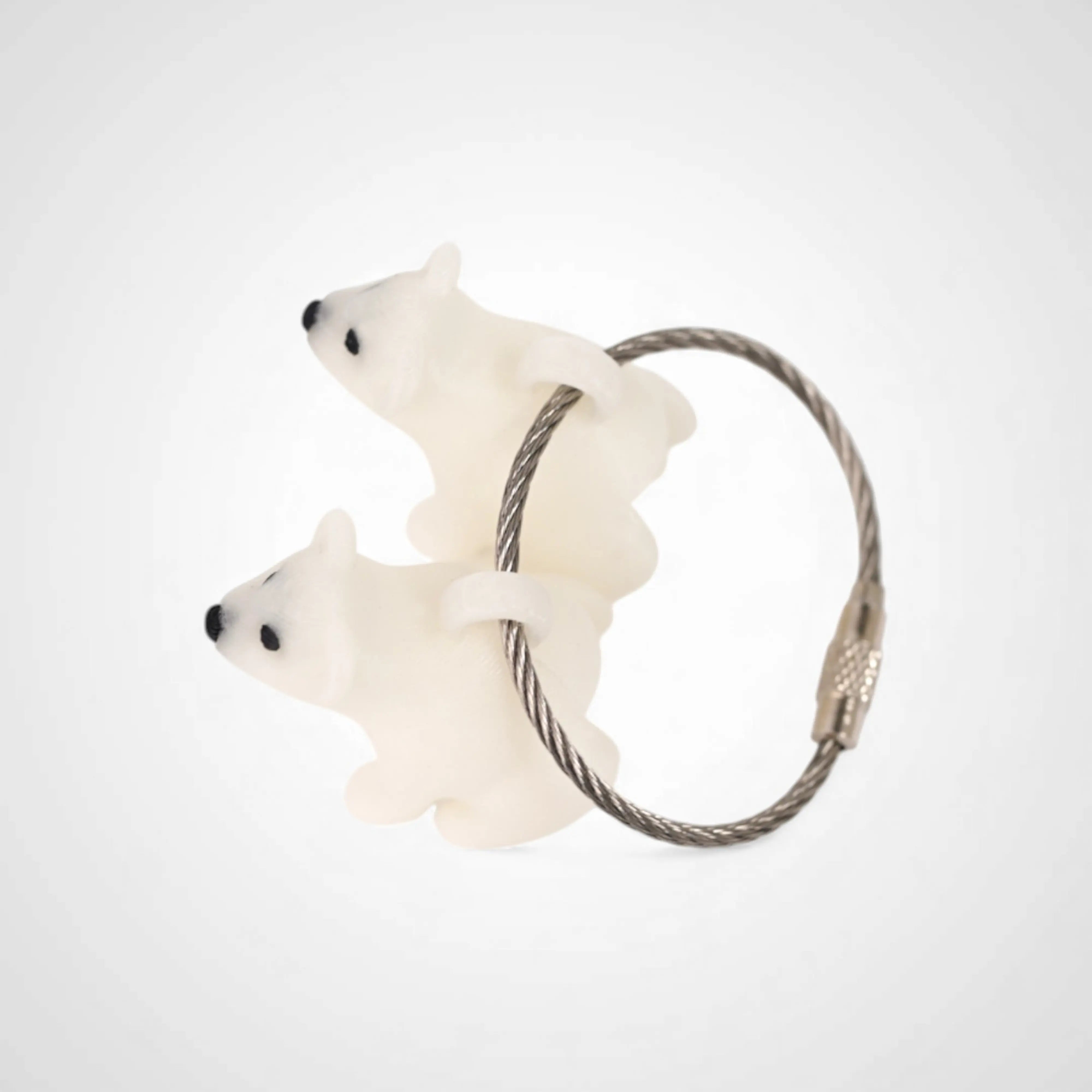 Two white polylactic acid created using additive manufacturing polar bear cap clips on steel cable keyring. Shown on a white background.