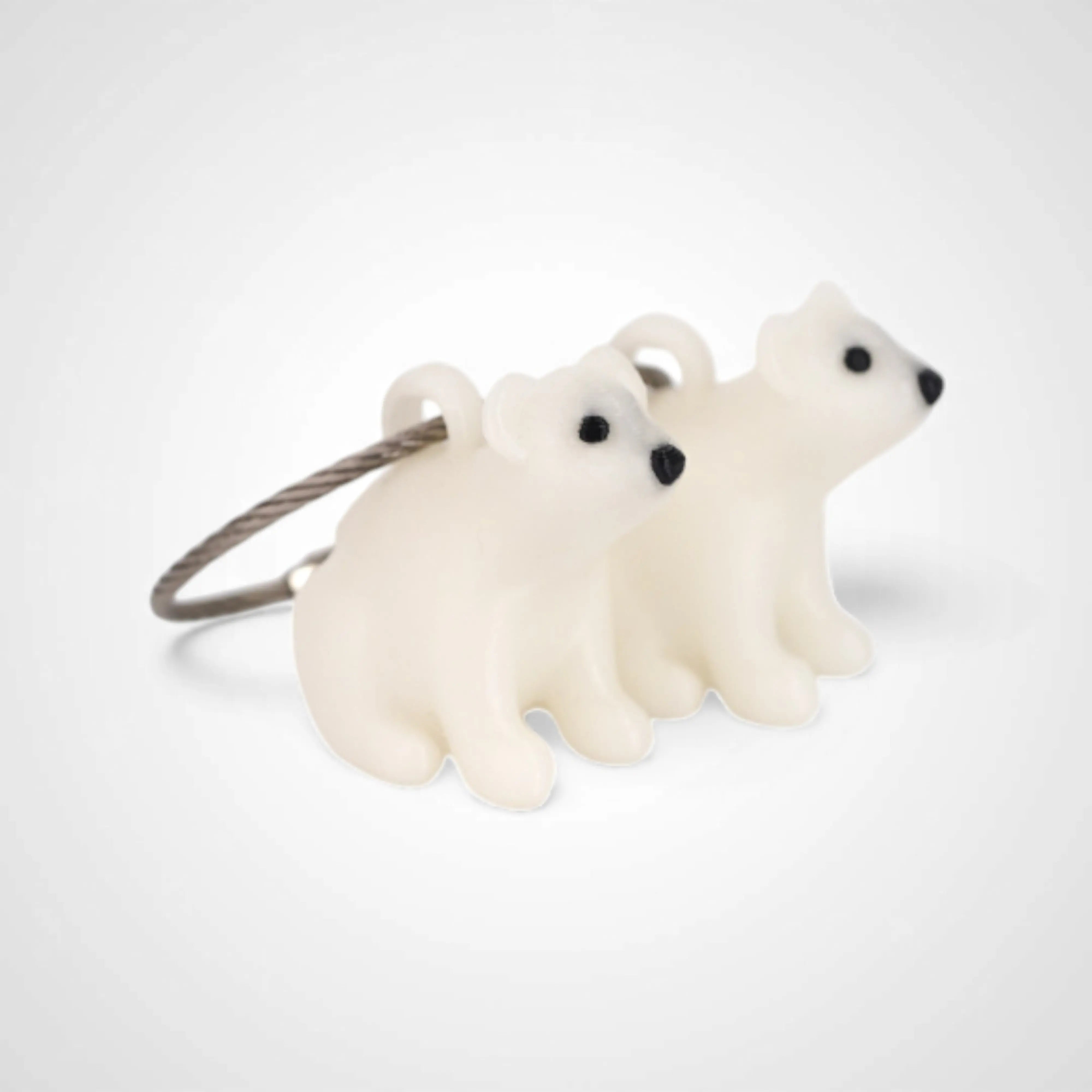 Two white polylactic acid created using additive manufacturing polar bear cap clips on steel cable keyring. Shown on a white background.