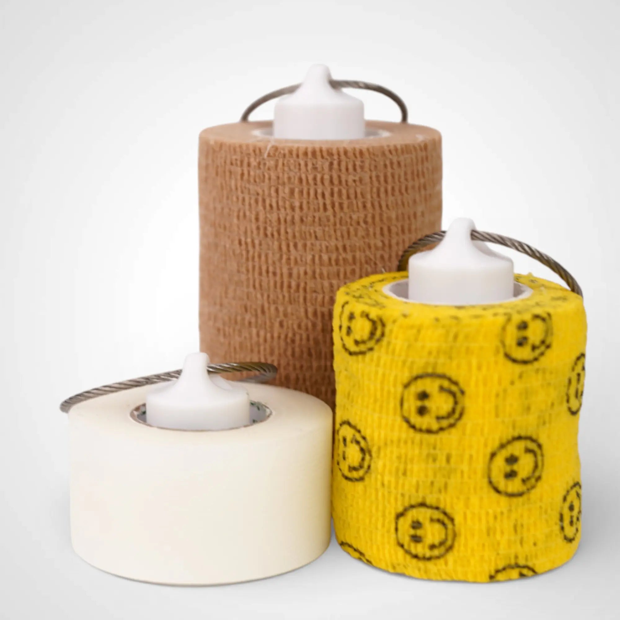 White roll holders made with polylactic acid, created using additive manufacturing for holding tape and bandage rolls. In three sizes, 1-inch, 2-inch, and 3-inch. With a steel cable keyring. All three sizes shown, with tape on them, on white background.
