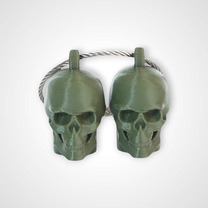 Two army green polylactic acid created using additive manufacturing skull cap clips on steel cable keyring. Shown on a white background.