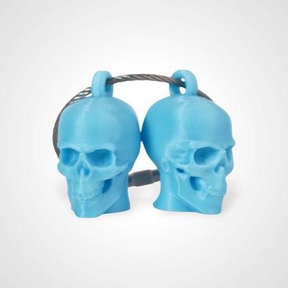 Two blue polylactic acid created using additive manufacturing skull cap clips on steel cable keyring. Shown on a white background.